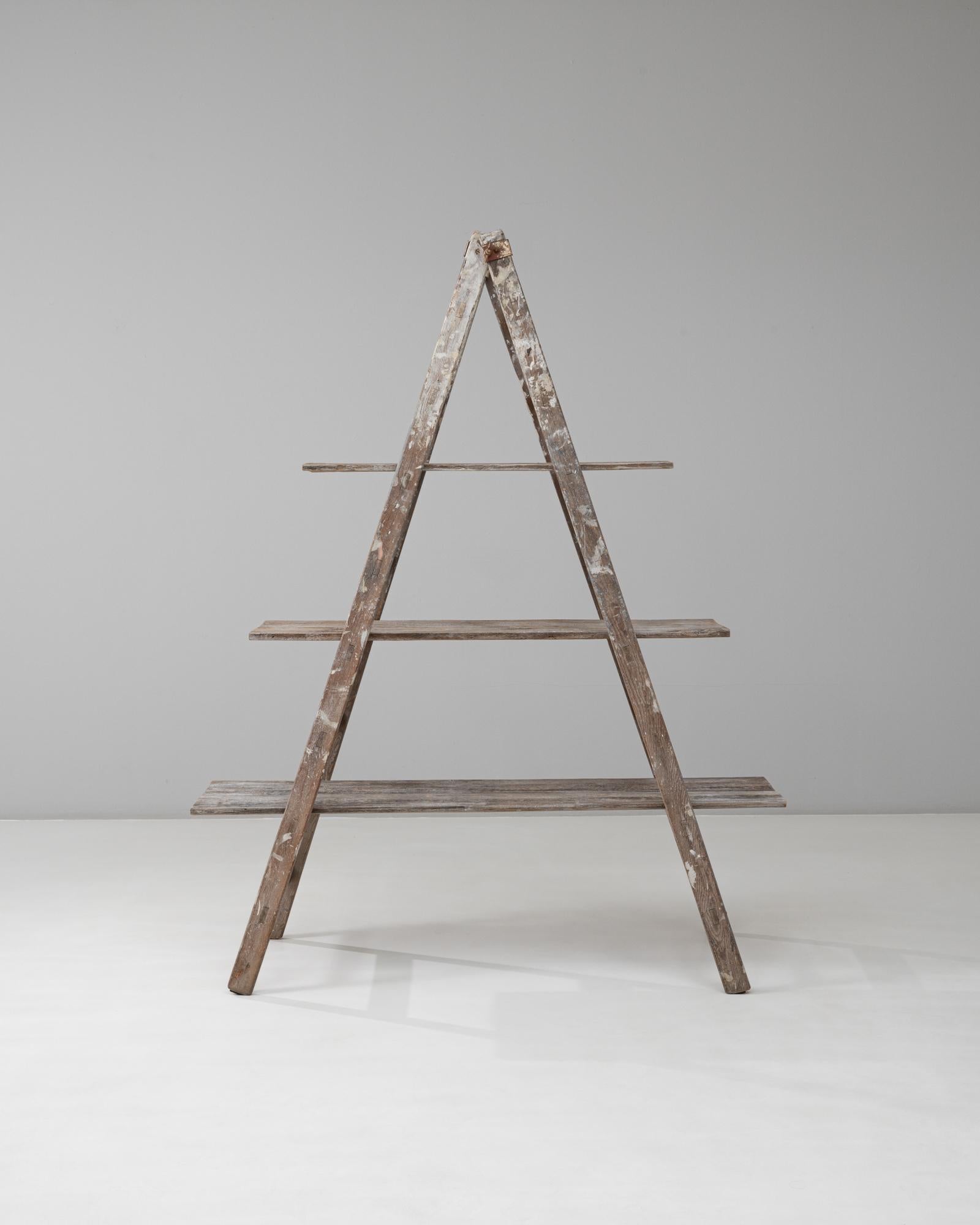 Questo scaffale francese con telaio ad A del XX secolo presenta una miscela perfetta di utilità rustica e fascino decorativo. Costruito in legno invecchiato con tracce di vernice originale, presenta tre ampie tavole sostenute da una struttura ad A,