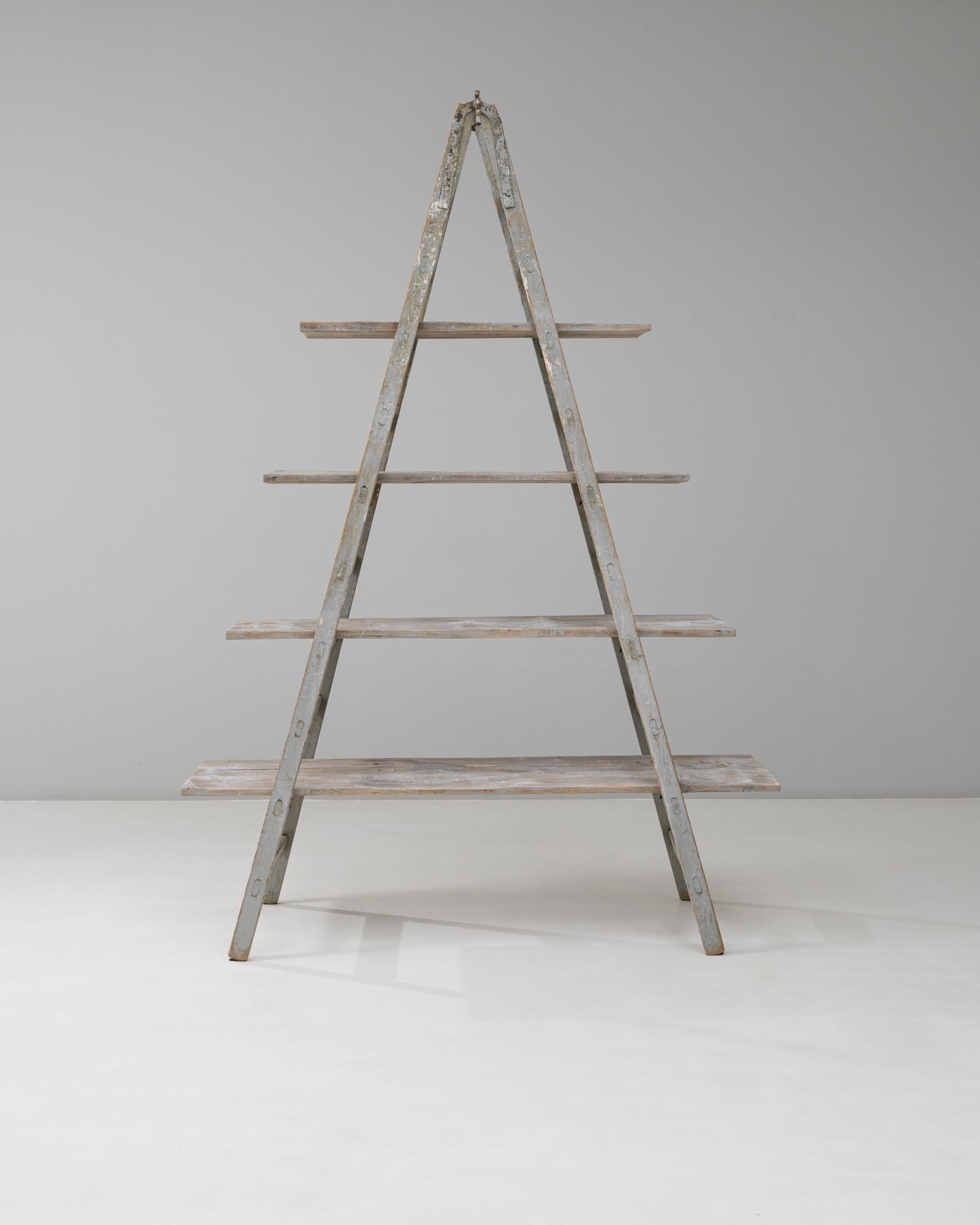 Questo scaffale francese con telaio ad A del XX secolo incarna l'utilità rustica e il carattere francese senza tempo. Realizzato in legno invecchiato con tracce di vernice originale, il pezzo presenta quattro livelli sostenuti da una robusta