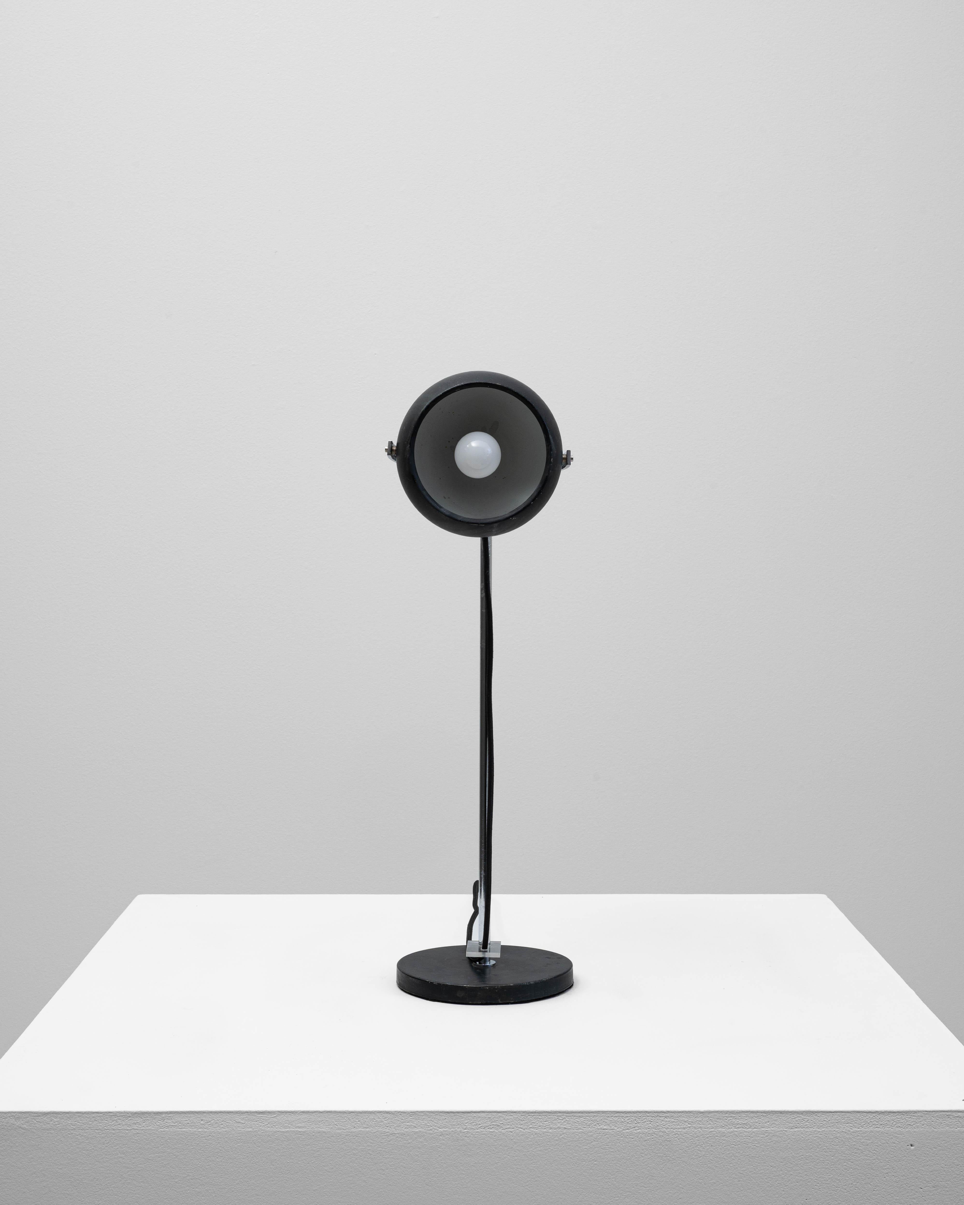 Exemple frappant du design français du milieu du siècle, cette lampe de table réglable en métal présente un abat-jour bombé noir épuré soutenu par une tige en chrome poli et une base circulaire noire. La structure minimaliste permet un éclairage