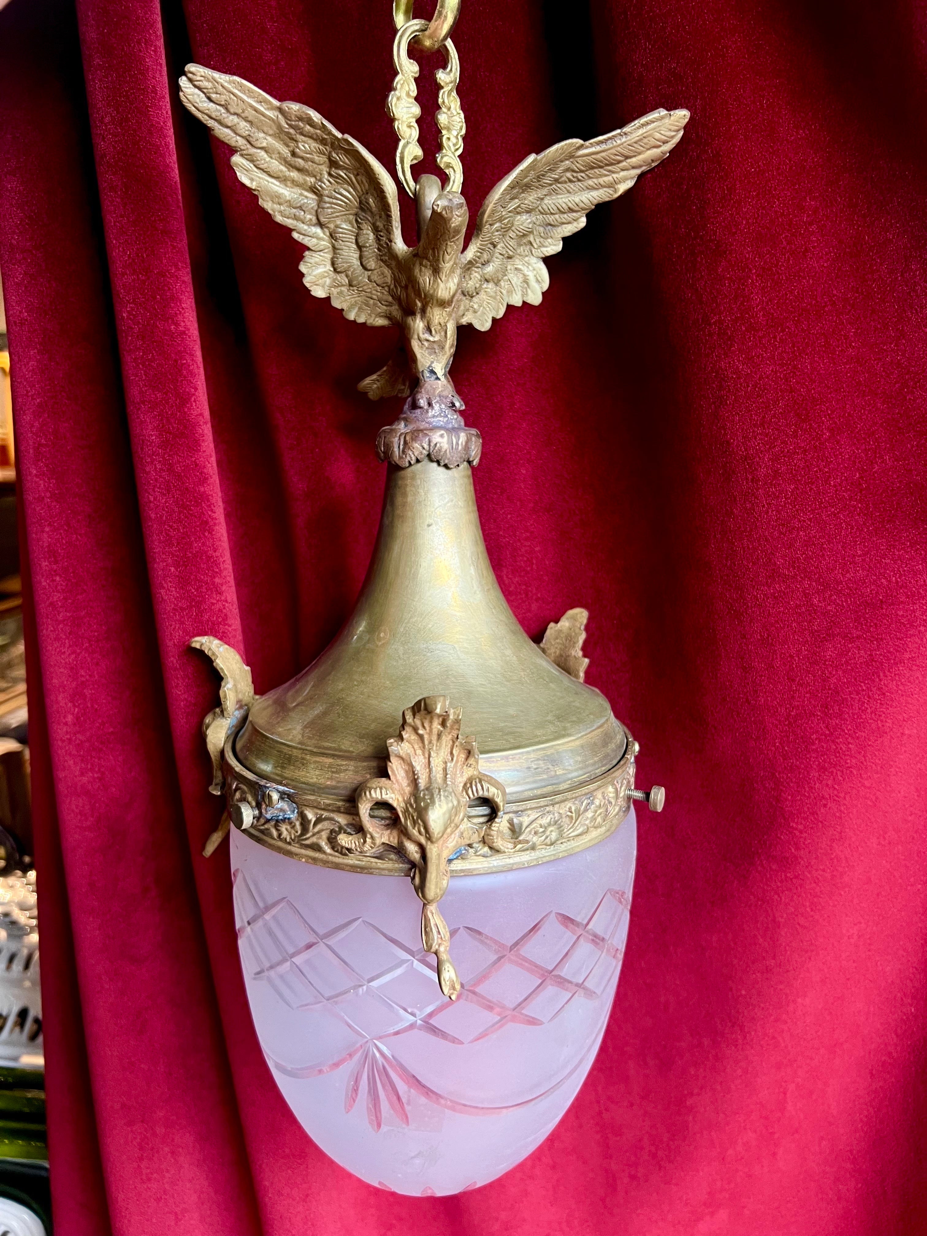 Lampada a sospensione antica francese del XX secolo realizzata in bronzo e decorata con una grande aquila sulla parte superiore. Ha una parte in cristallo originale incisa sul fondo con una lampadina all'interno. Condizioni molto buone con una