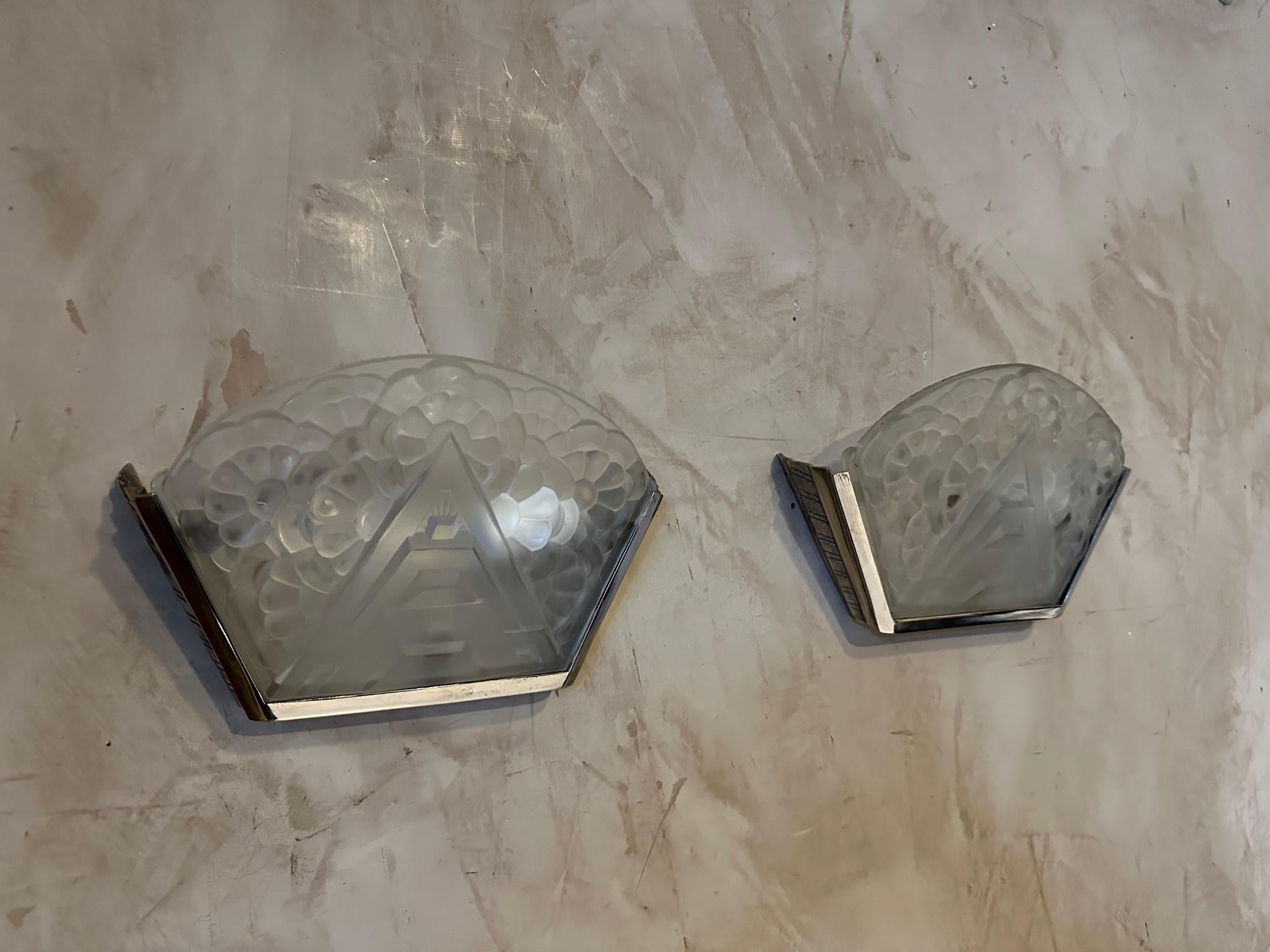 Very beautiful pair of art deco wall lights in tempered glass engraved with flowers and graphic lines typical of the Art Deco years.
Chromed metal frame also with beautiful graphics.
Signature on the glass. Good quality and good condition.
For art