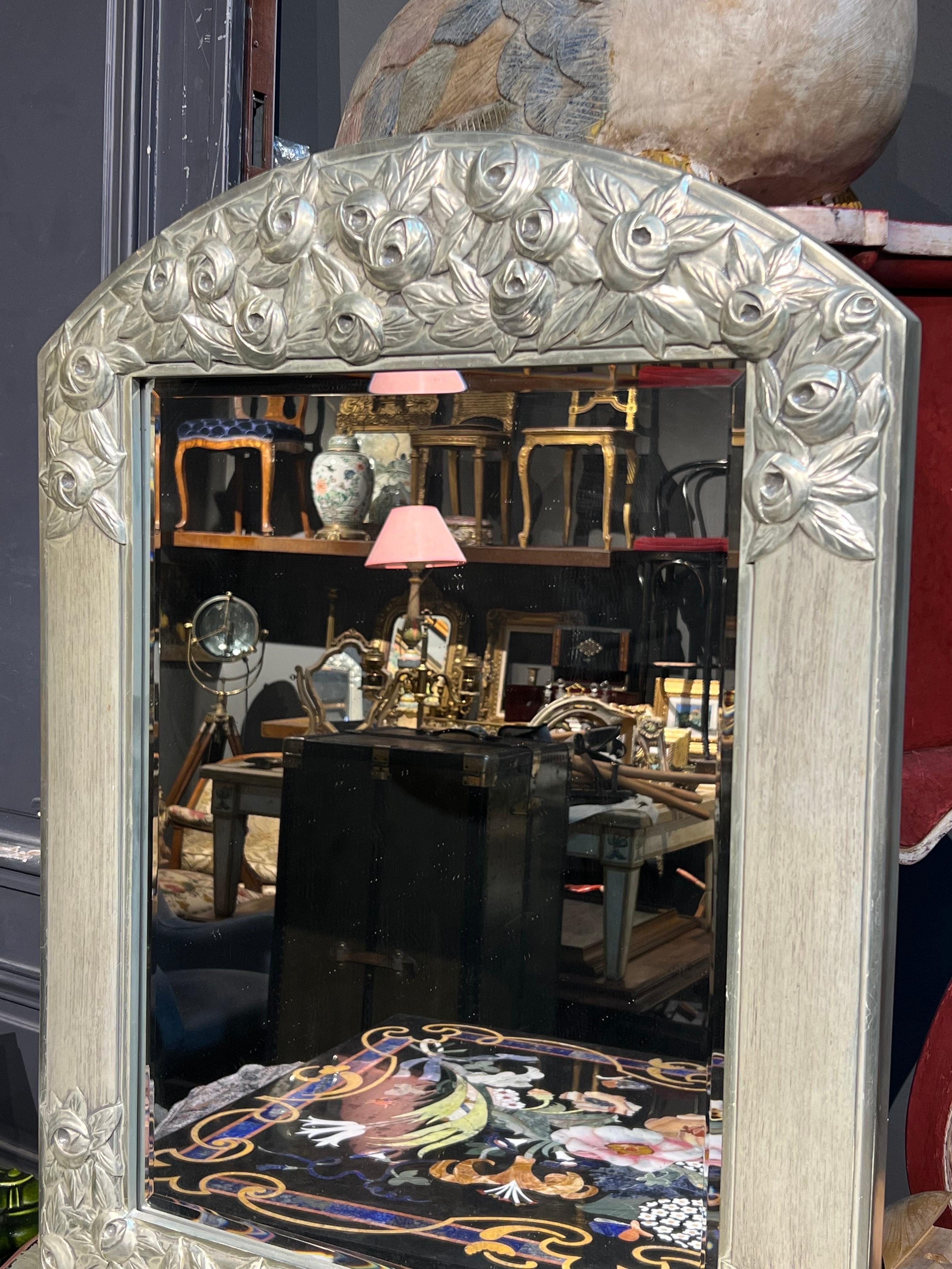 Miroir en bois sculpté à la main Art Déco français du 20e siècle, décoré de roses peintes à la main en couleur argentée. Belle pièce qui, de loin, ressemble à du métal. 
France, vers 1920