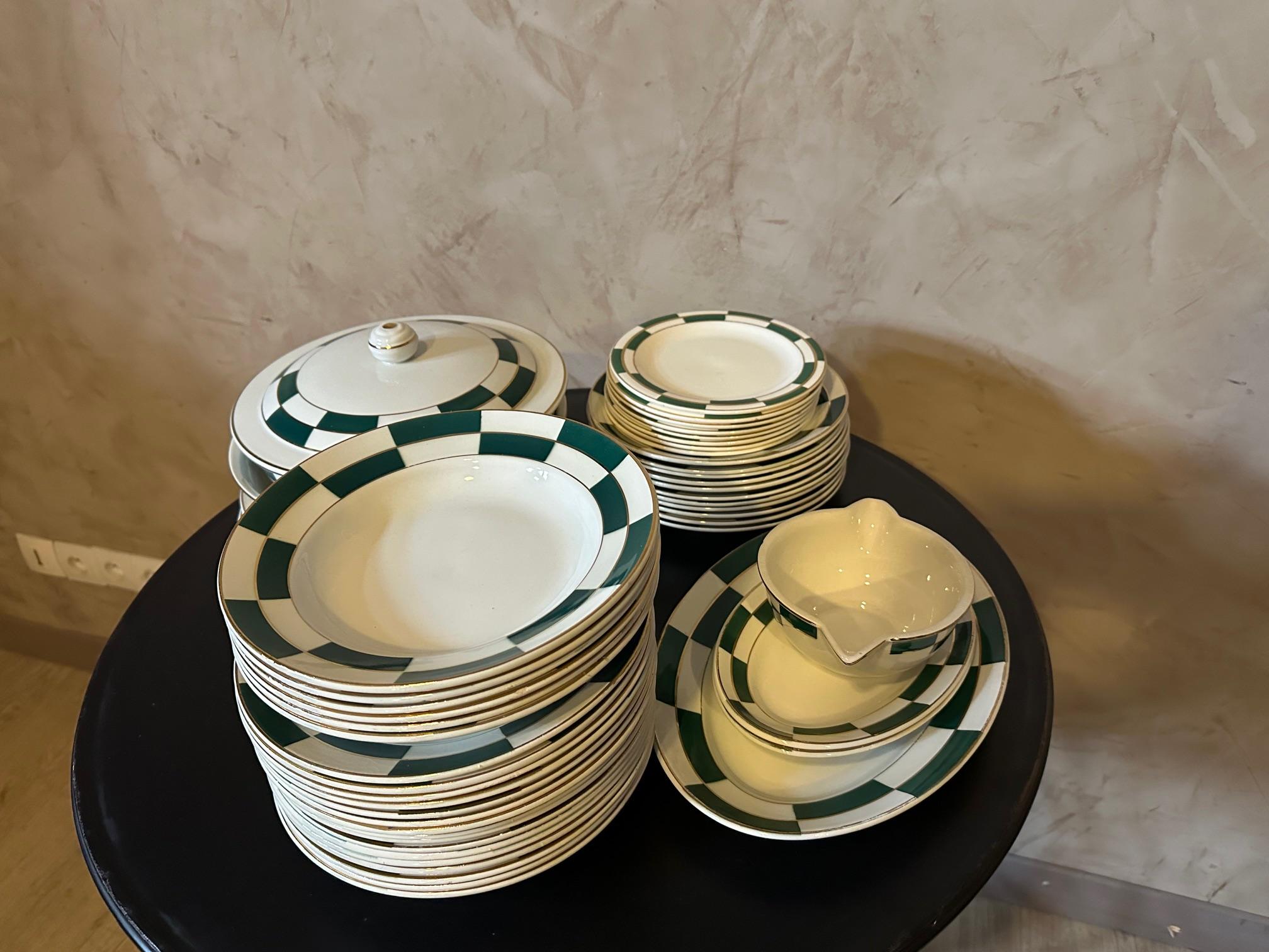 Très beau service art déco en porcelaine opaque de la faïencerie de Luneville à décor graphique vert et filet doré. 
Ce service est composé de : 21 assiettes plates (5 légèrement ébréchées) 12 assiettes creuses. 8 assiettes à dessert (1 abîmée) 3