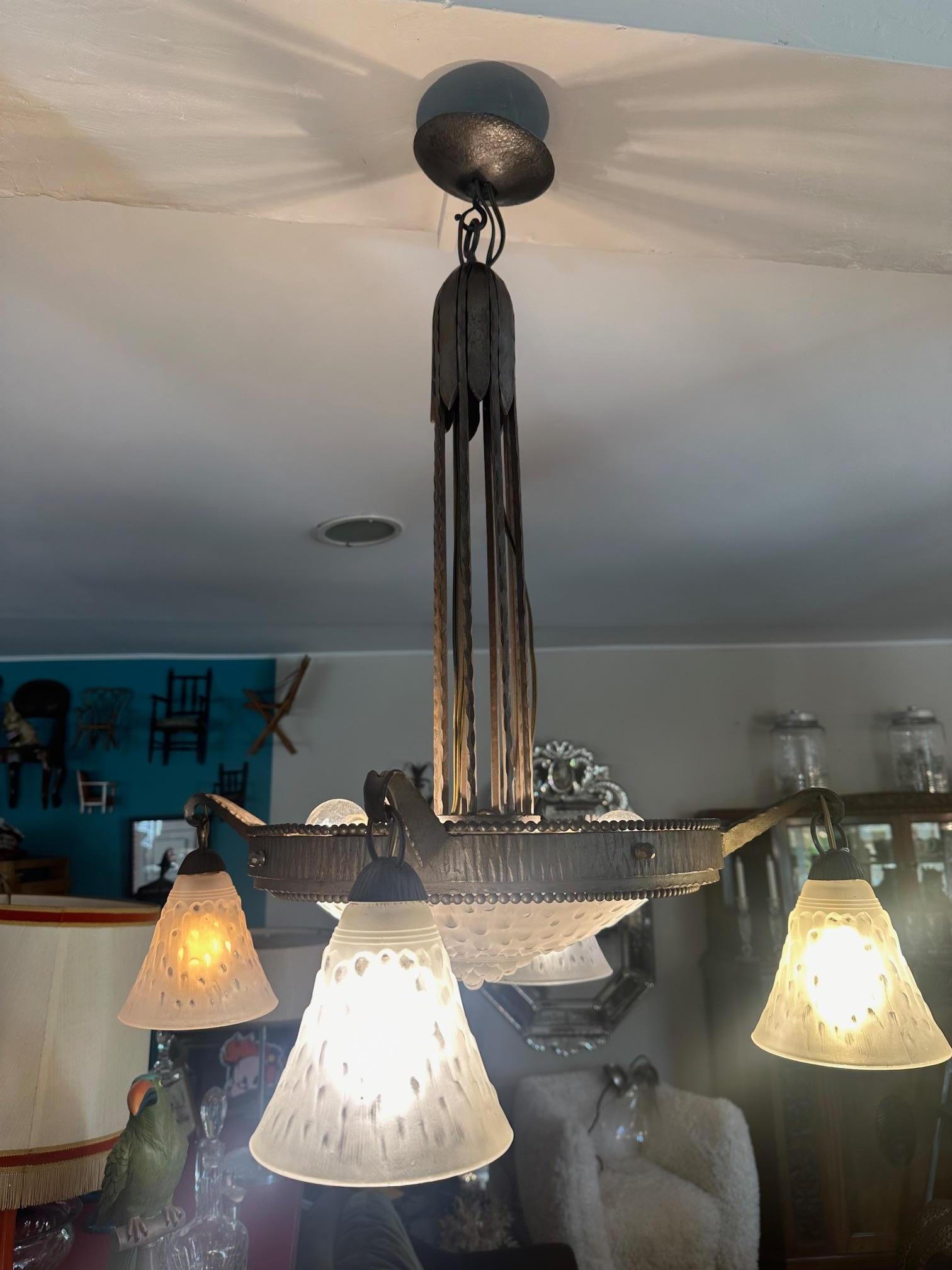 Beautiful Hammered wrought iron chandelier decorated with beaded rows in a belt. It is composed of a basin and 4 tulips. 
We can find this model of chandelier in the catalog of the ironworker (V. & Cie, for Marcel Vasseur et Cie) under the reference