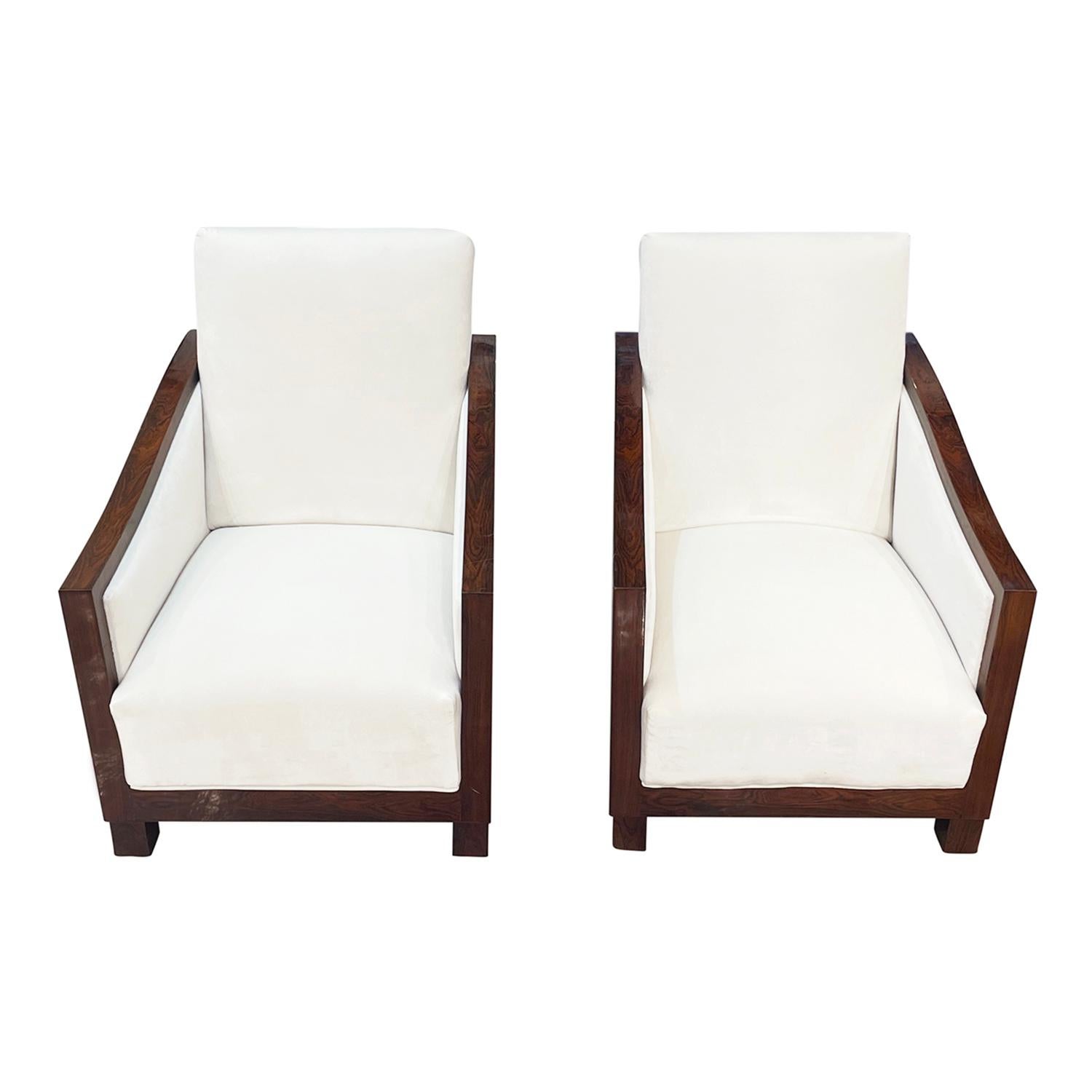 A vintage Art Deco French pair of cocktail club chairs made of hand crafted polished, partly veneered Walnut, in good condition. The Parisian solid wooden library armchairs have an inclined backrest, detailed with arched arms which are partly