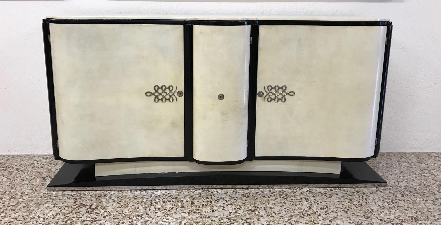 This magnificent Art Deco sideboard was produced in France in the 1930s.
Its majestic lines are embellished with fine parchment.
The edges are ebonized while the decorations on the doors are in chromed metal like the profile on the base.
The very