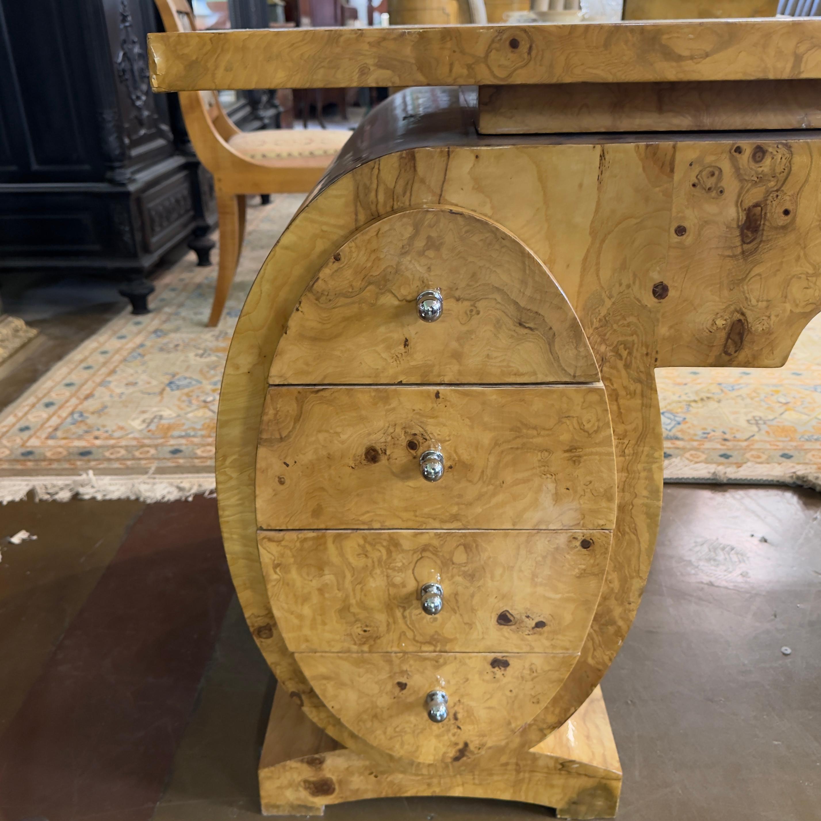 Elevate your workspace with this exquisite Art Deco olive burl desk, where timeless elegance meets modern functionality. Crafted from the finest olive burl wood, this desk boasts a rich, natural grain that is beautifully accentuated by a lustrous