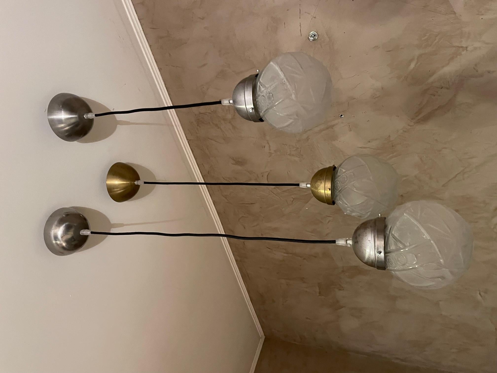 Ensemble de 3 globes art déco transformés en luminaires suspendus. Deux sont avec un support en métal chromé et l'autre est en laiton. Fil noir. Jolis globes terrestres typiques des années 30. Possibilité d'acheter individuellement. Système réglable