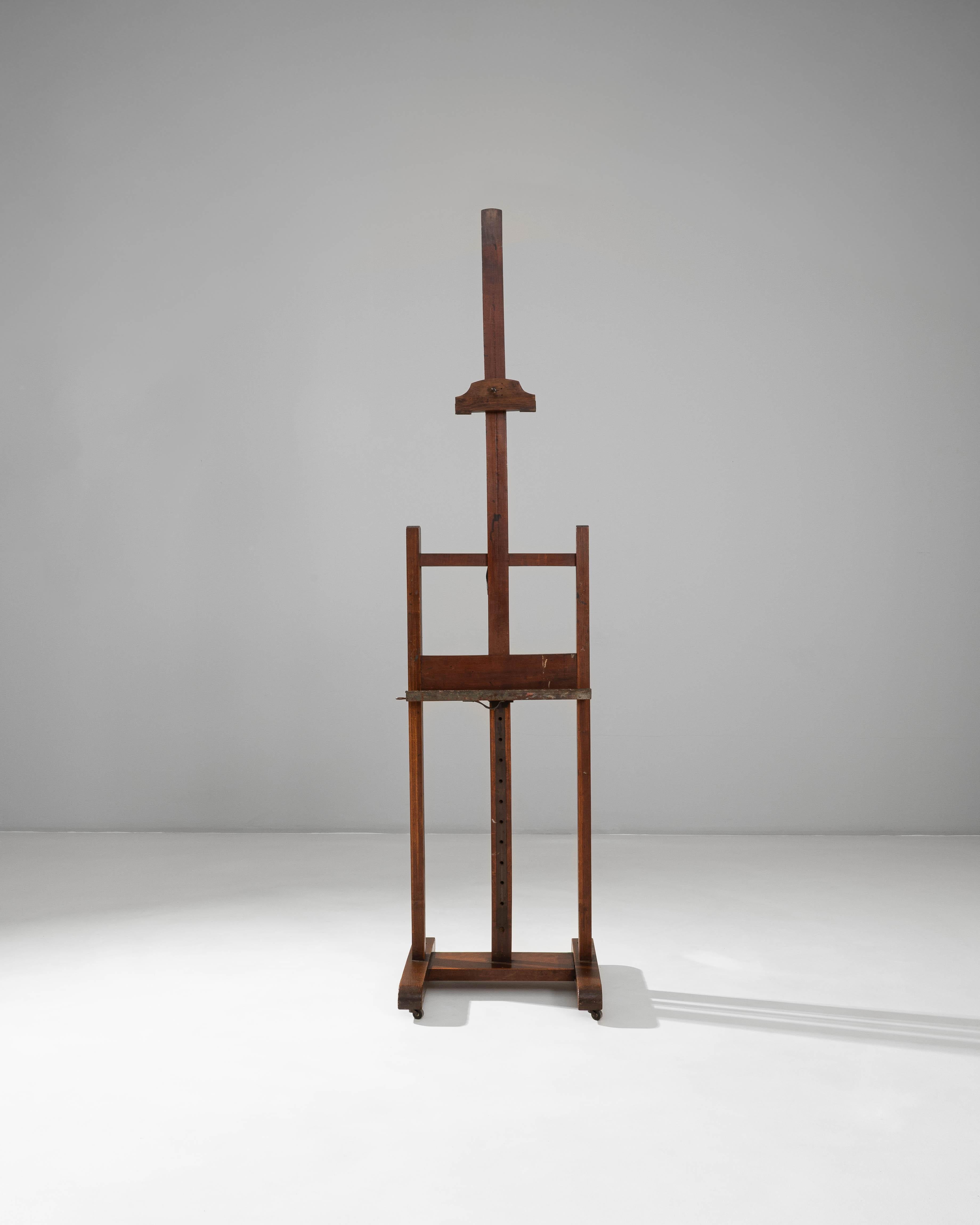 Este caballete de madera de artista francés del siglo XX encarna la elegancia funcional del equipo de estudio tradicional. Fabricado en madera maciza con una cálida pátina desgastada por el tiempo, el caballete cuenta con un mástil central ajustable