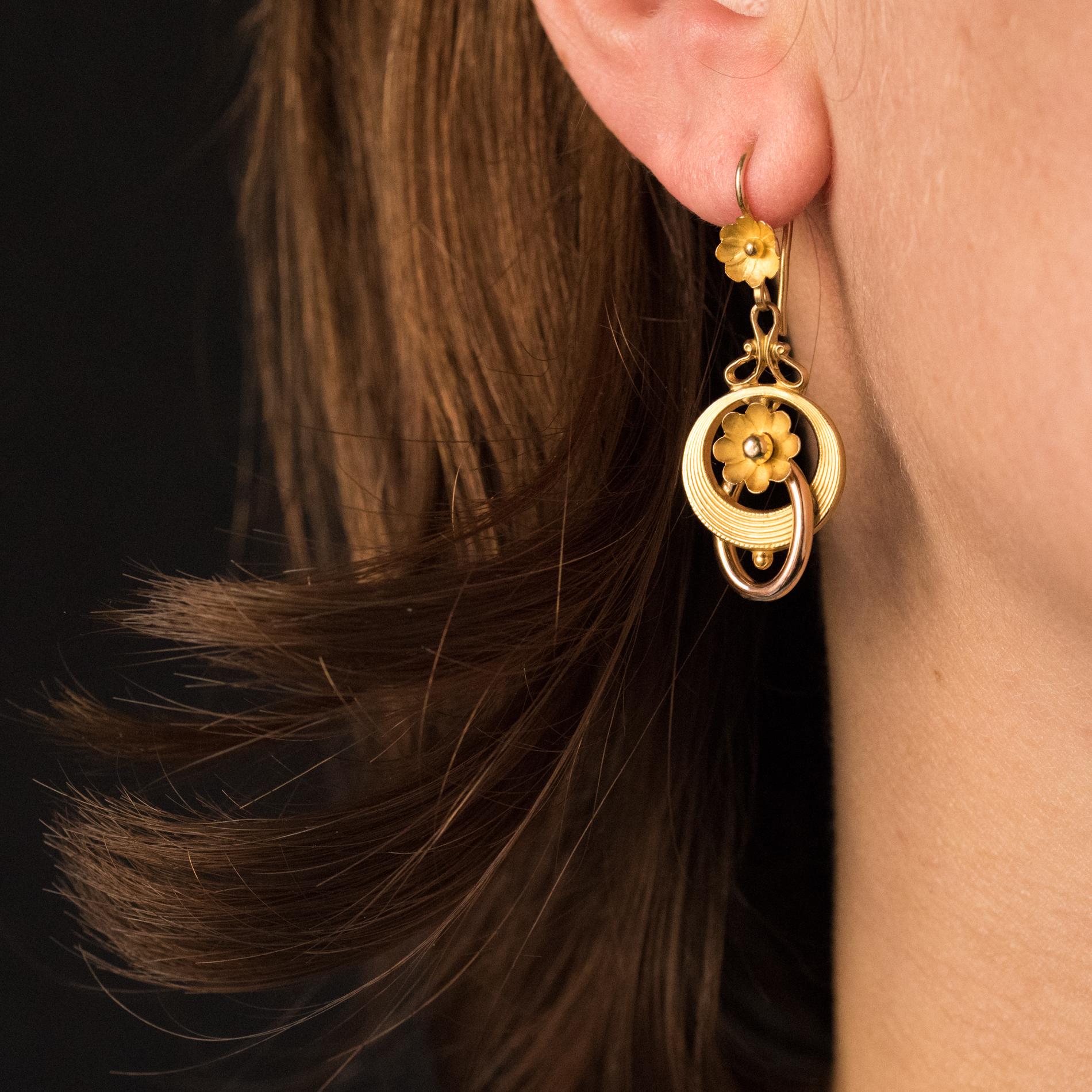 Earrings in 18 karats yellow gold, eagle's head hallmark.
Lovely dangle earrings, they are composed of a motif representing a flower that holds a pendant made of 2 circles of gold imbicated, one of round section and oval, the other flat and