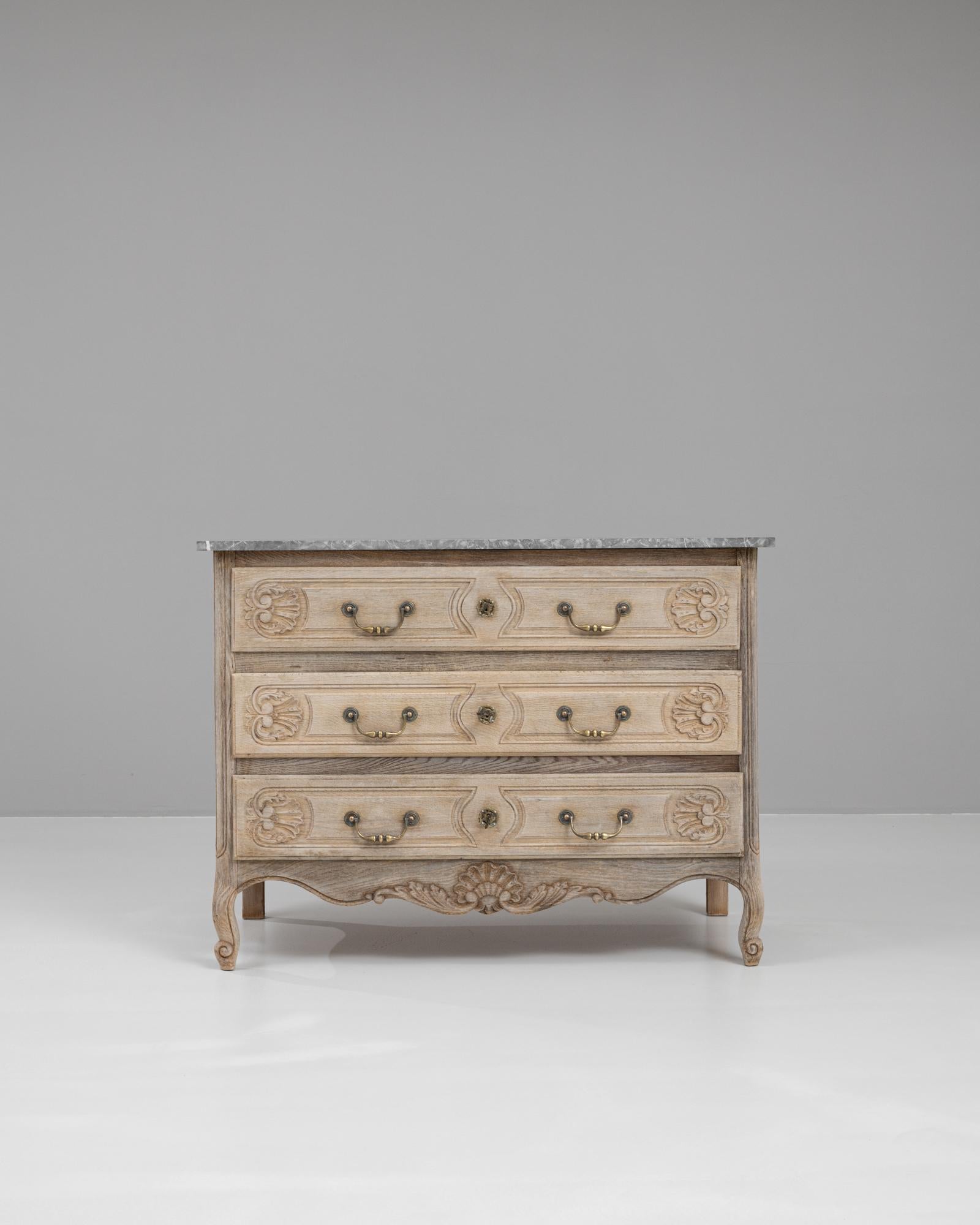 This exquisite 20th-century French chest of drawers combines timeless elegance with practical functionality. Crafted from bleached oak, it features beautifully carved detailing on the front and sides, showcasing the intricate artistry typical of