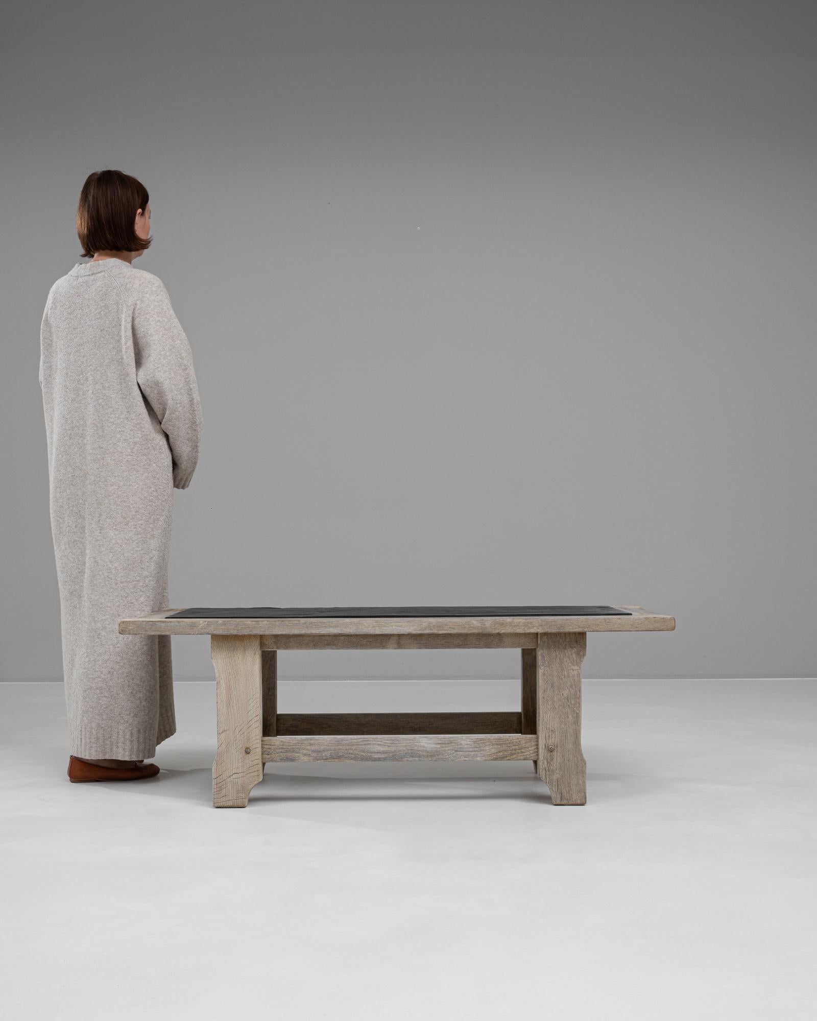 Cette table basse française du XXe siècle est un exemple étonnant de sophistication rustique. Fabriquée en chêne blanchi, sa construction robuste met en évidence une texture altérée qui dégage un charme intemporel. Le plateau de la table est