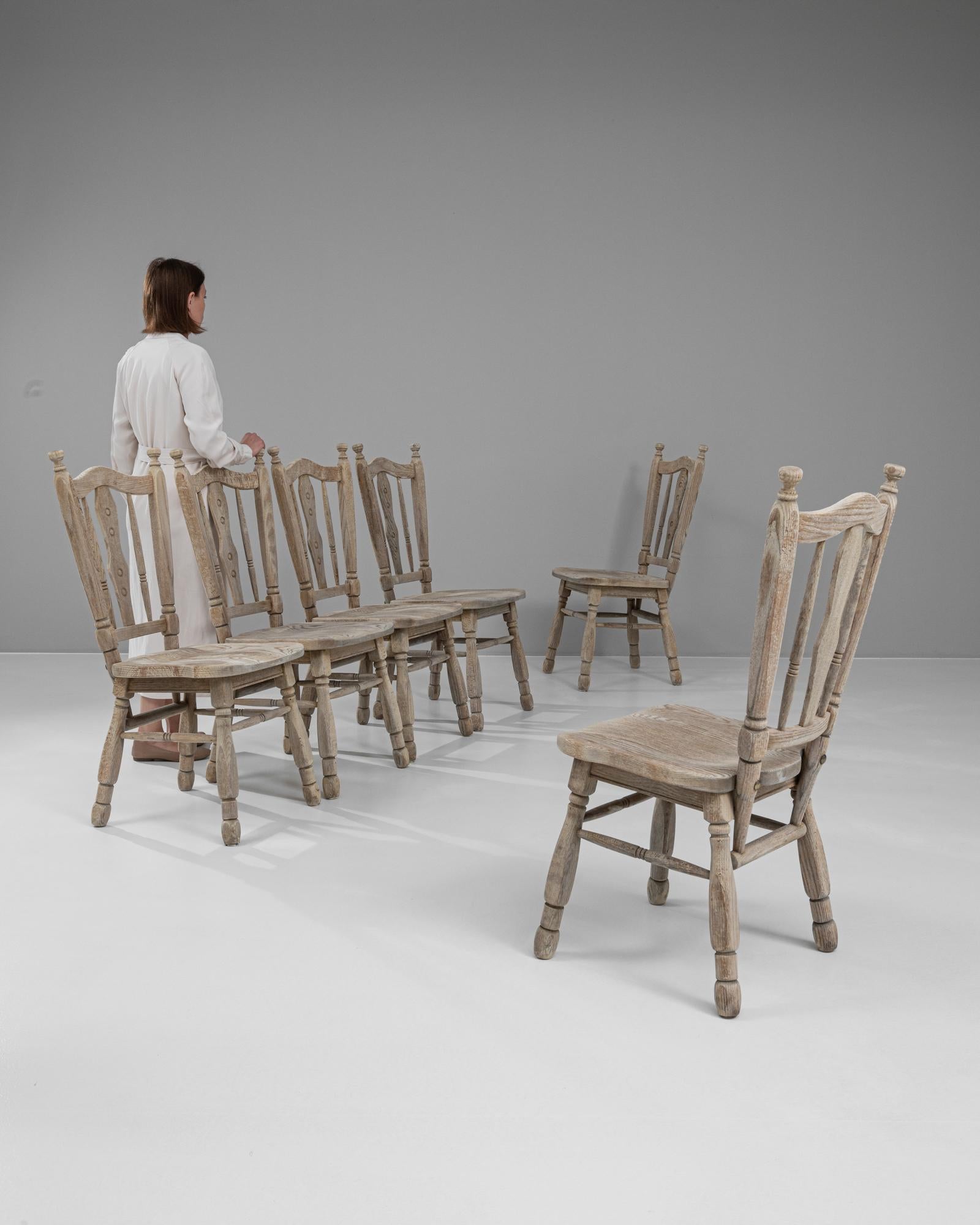 Aggiungi un tocco di charme della campagna francese alla tua sala da pranzo con questo splendido set di sei sedie da pranzo in rovere sbiancato francese del XX secolo. Ogni sedia è realizzata meticolosamente in rovere di alta qualità e presenta una