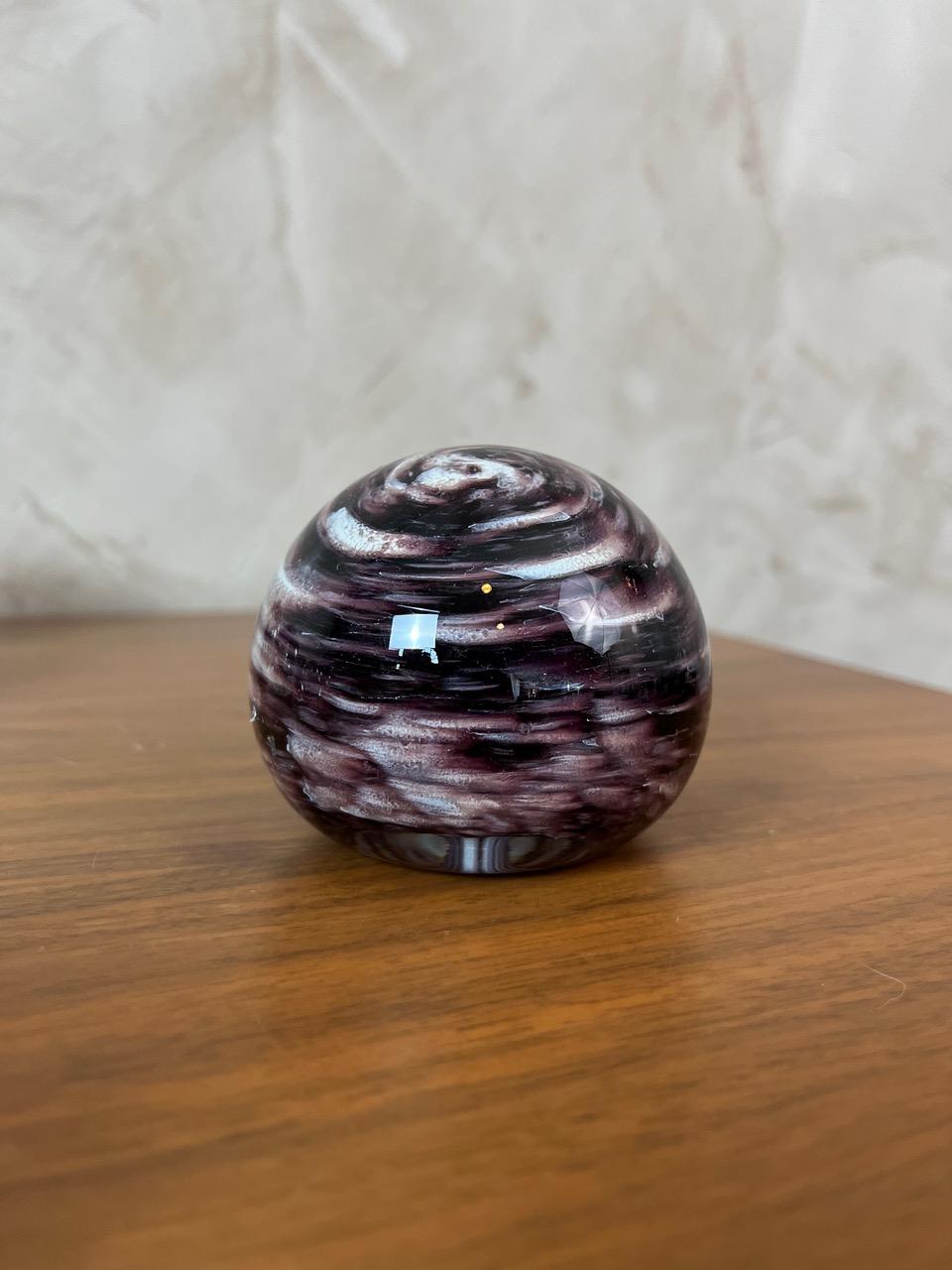 Presse-papiers en verre soufflé ou sulfure de verre, captivant par son motif en spirale aux tons violets profonds et au blanc nacré. Une pièce décorative qui apportera une touche d'élégance et de mystère à votre bureau ou à n'importe quelle étagère.