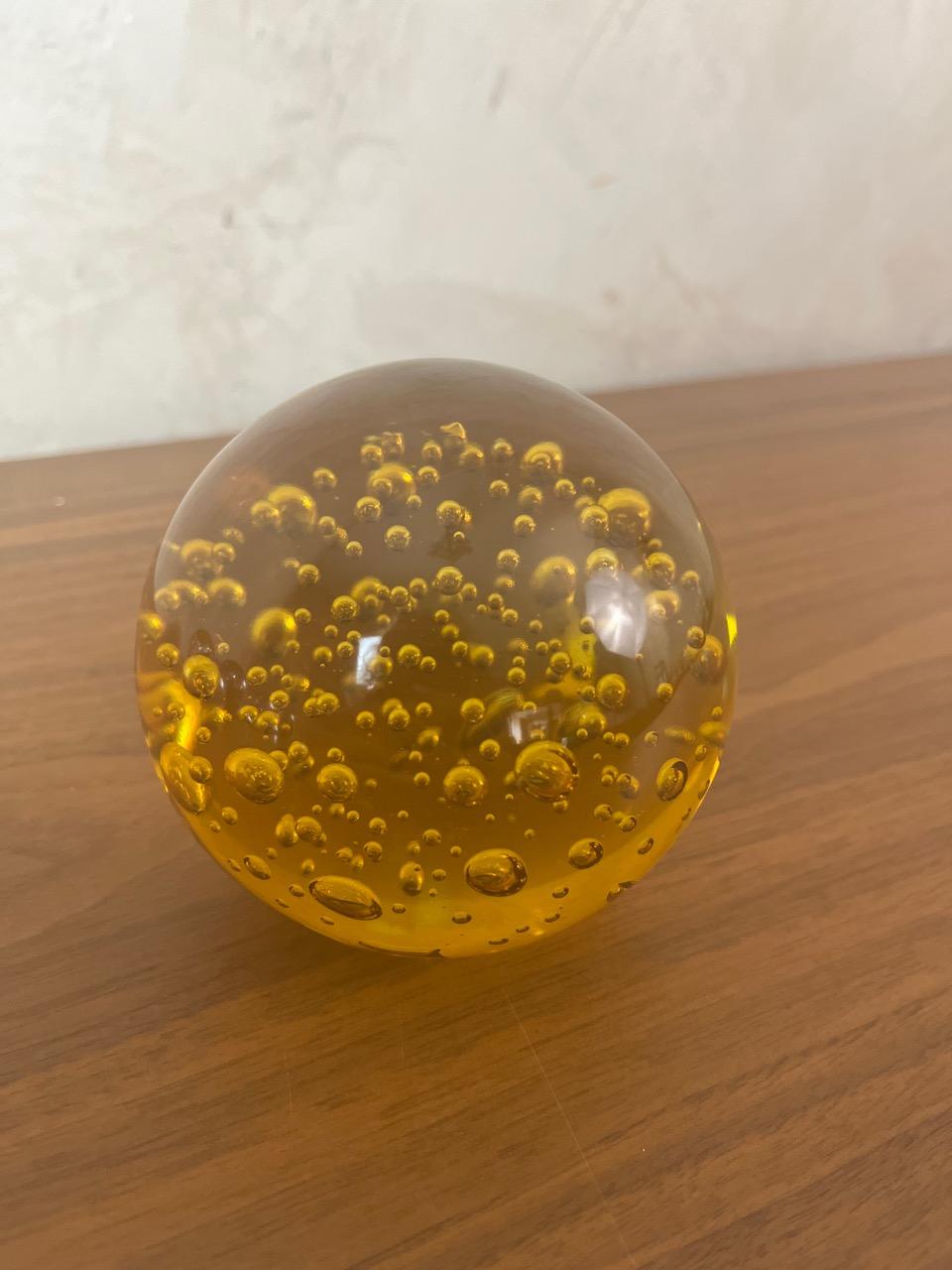 Amber-colored blown glass paperweight/sulphide, filled with a multitude of air bubbles that create a fascinating visual effect. An elegant and luminous piece for your desk, a shelf, or as a collectible item.