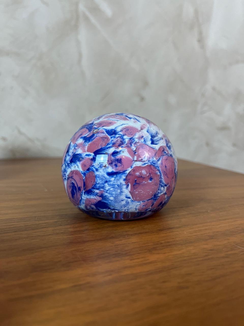 Presse-papier en verre soufflé ou sulfure de verre. Sa composition vibrante de motifs bleus et roses entrelacés en fait une petite œuvre d'art, parfaite pour égayer un bureau, une étagère ou comme pièce de collection.