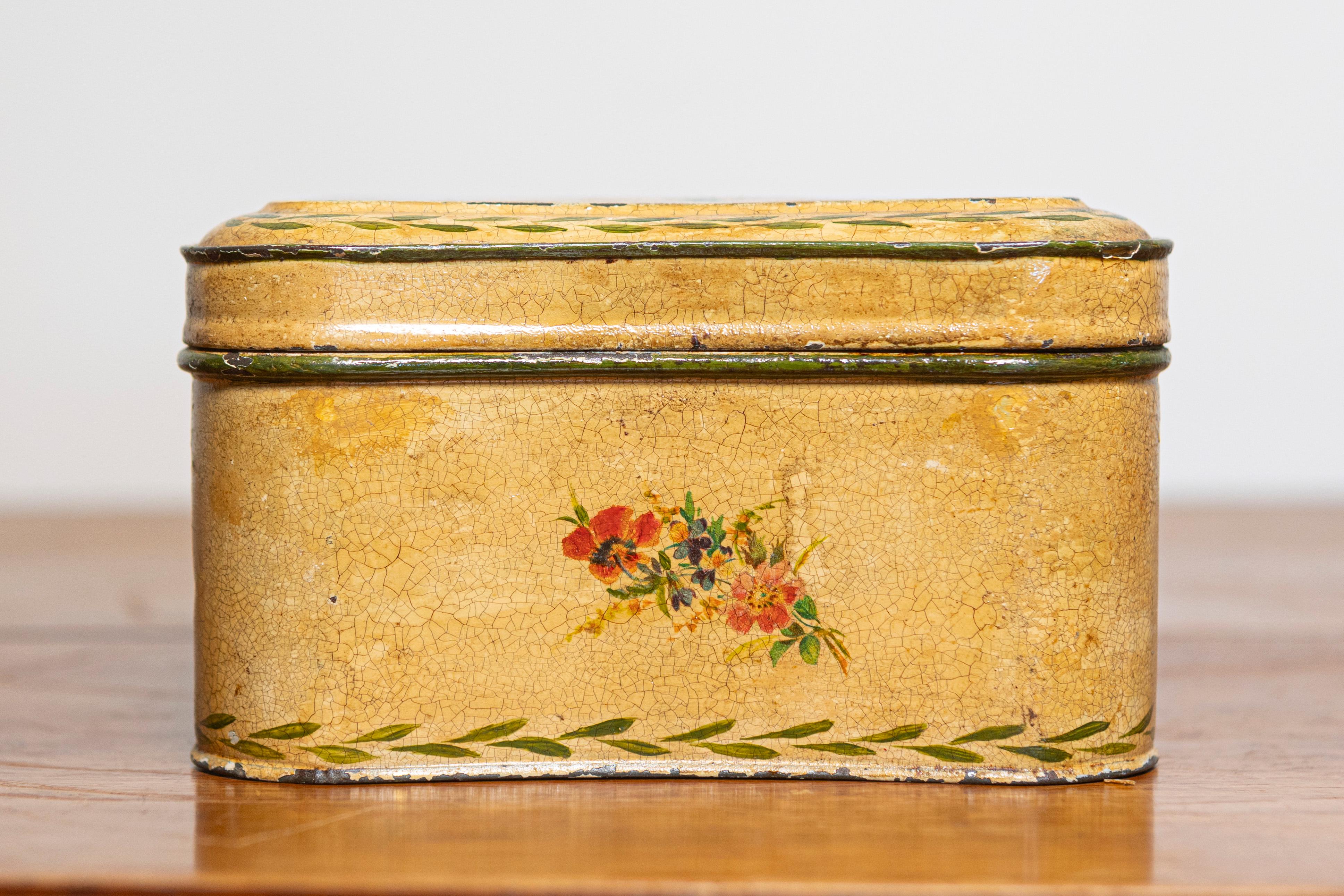 Questa affascinante scatola francese del XX secolo è sapientemente realizzata in lamiera e adornata con squisite decorazioni floreali dipinte a mano. Su un morbido sfondo beige, il disegno presenta rose vivaci, fogliame verde e bordi intricati,