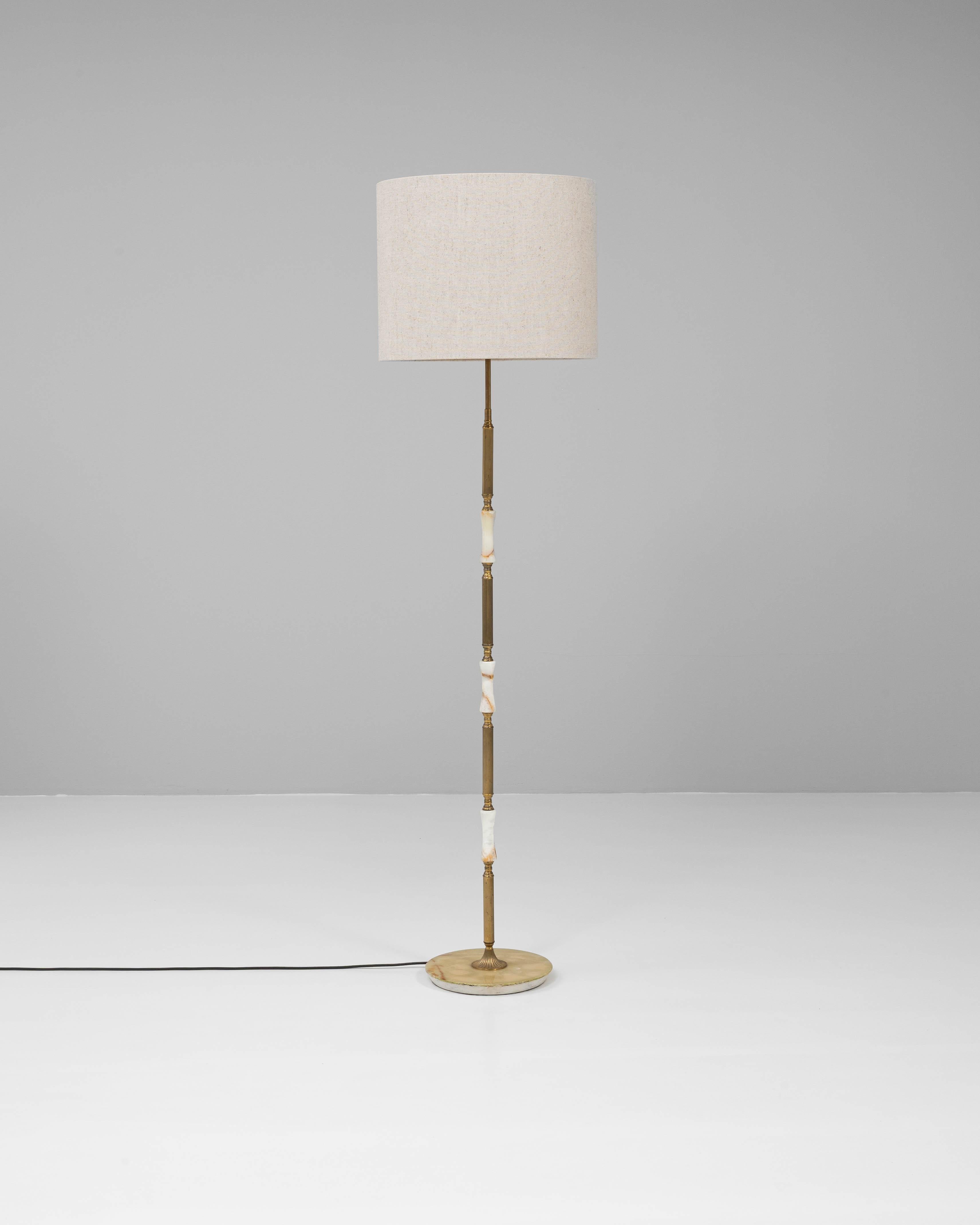 Ce lampadaire français du XXe siècle est une composition raffinée de laiton et d'albâtre, mêlant des matériaux classiques à une élégance discrète. La tige élancée en laiton présente des détails cannelés et est ponctuée d'accents sculpturaux en