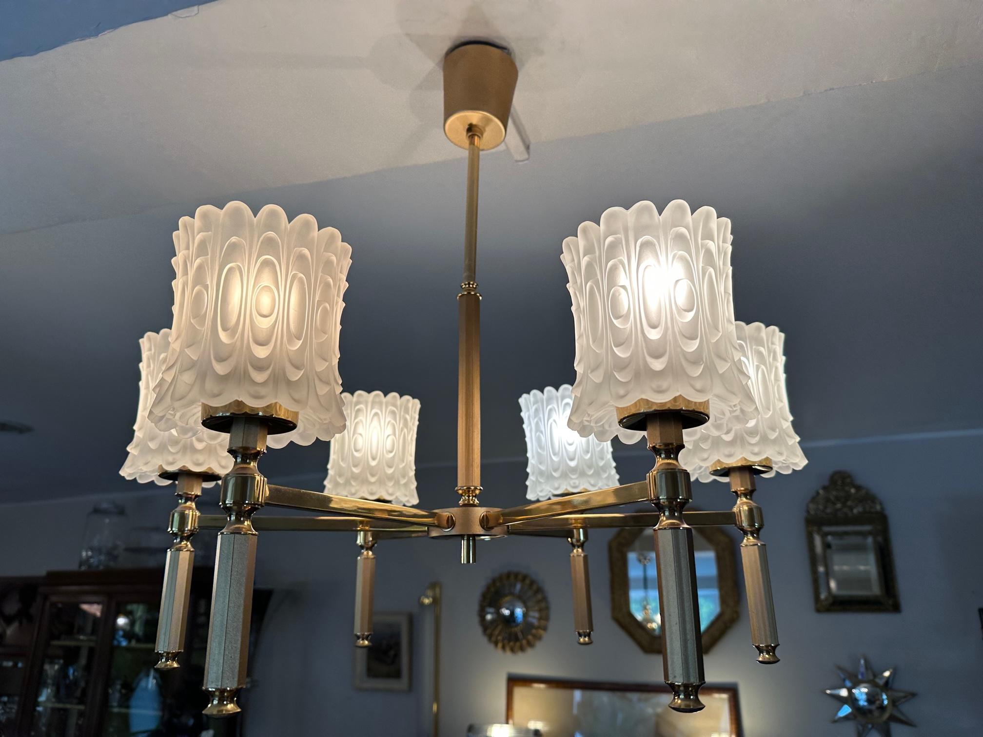 Very beautiful chandelier from the 70s in brass and six sculpted and opaque glass lampshades. Very good condition. 
Very elegant design and bright light.
For lovers of vintage and beautiful decorative pieces.