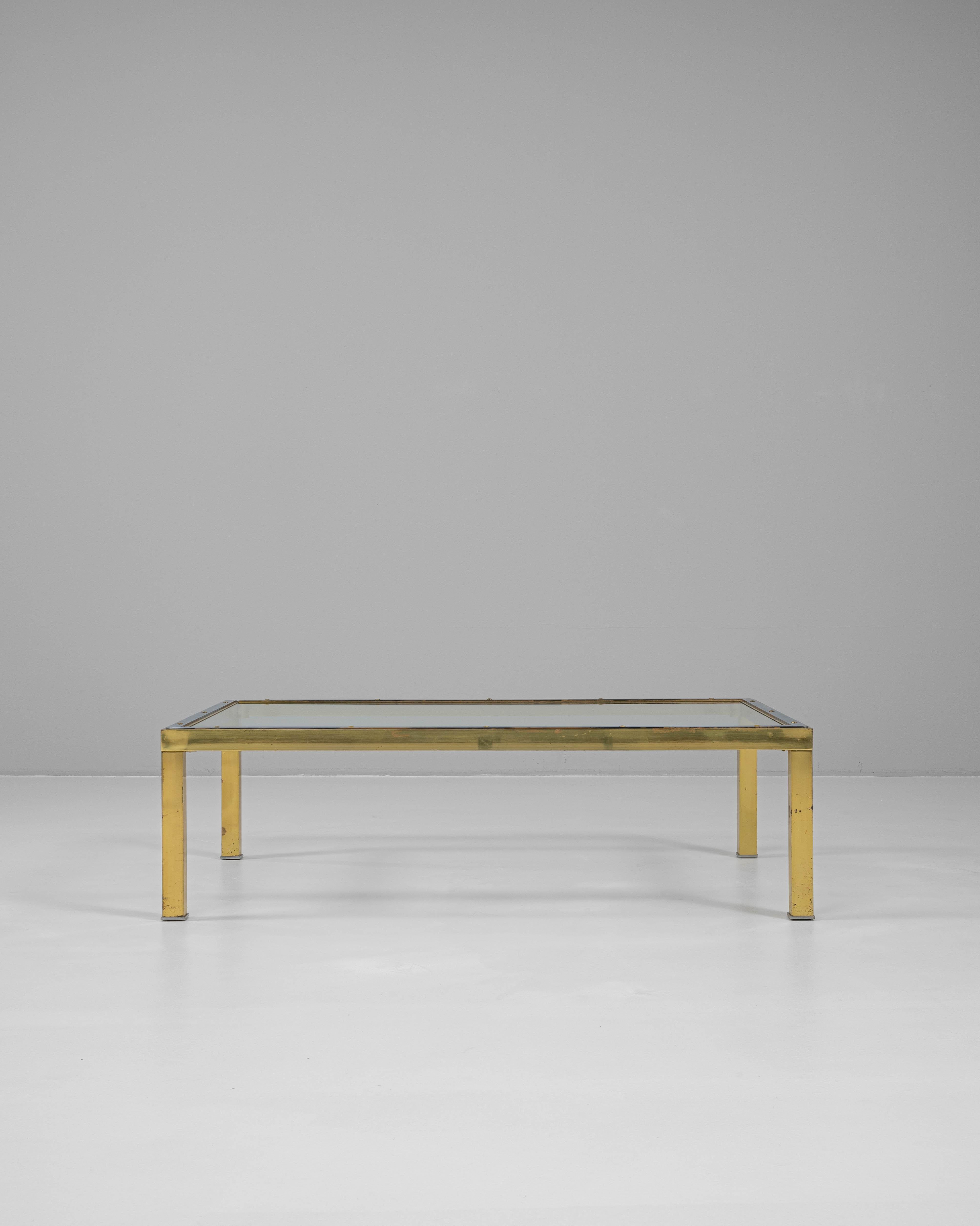 Cette table basse en laiton français du XXe siècle avec un plateau en verre est une pièce remarquable qui allie harmonieusement l'esthétique industrielle et moderne. Le cadre en laiton robuste présente une patine riche et usée par le temps, ce qui