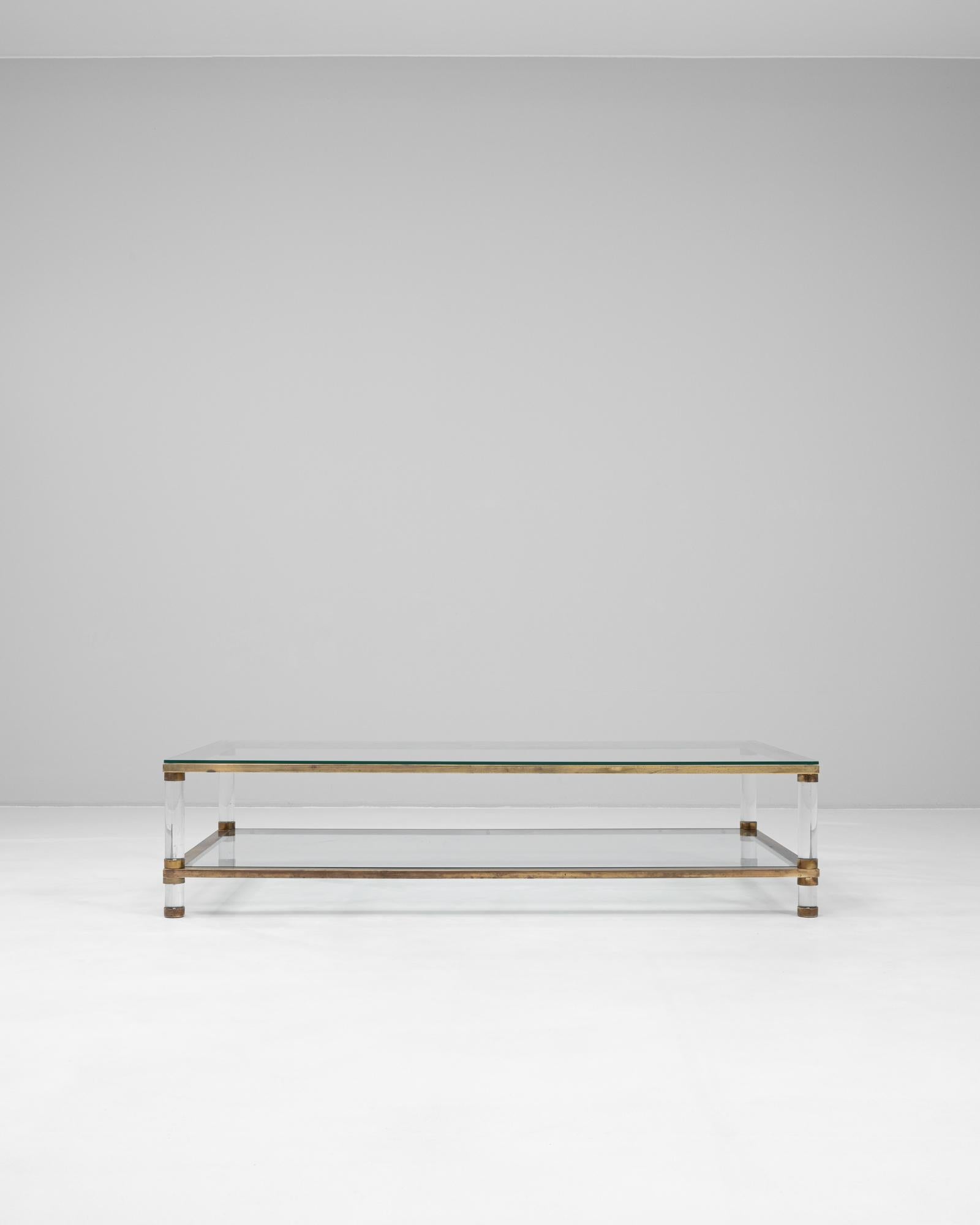 Esta mesa de centro francesa del siglo XX presenta un diseño elegante y modernista que combina elementos de latón, cristal y lucita. La parte superior rectangular es de cristal grueso, enmarcado en latón envejecido para un cálido contraste metálico.