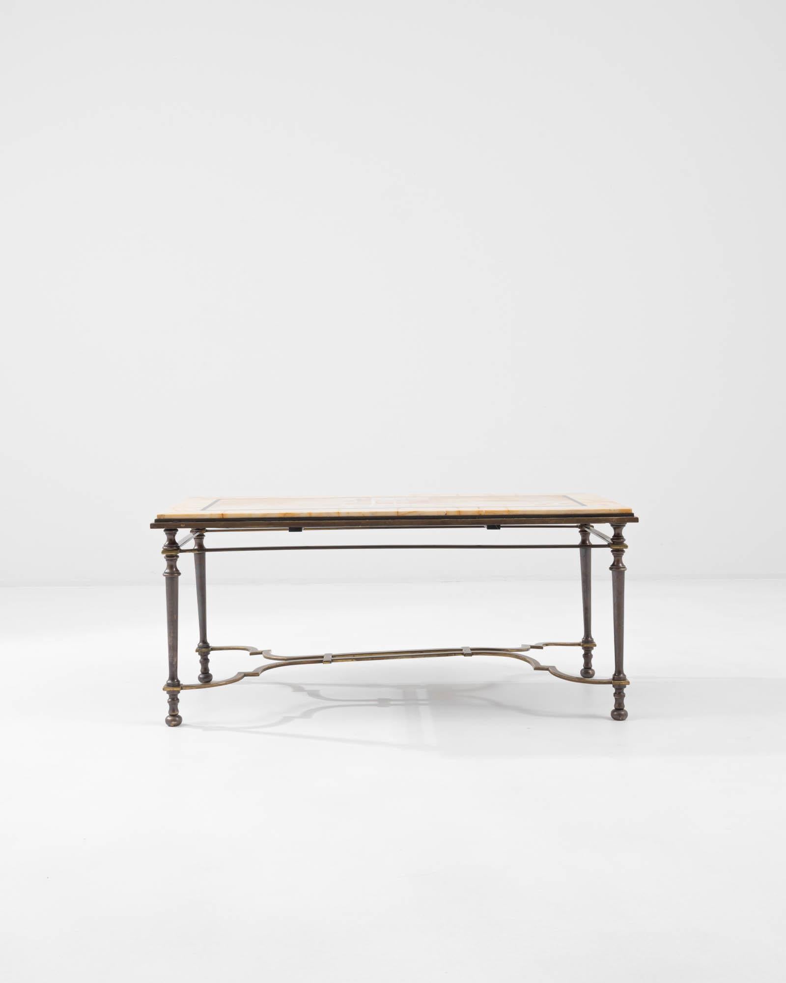 The elegant symmetries of this vintage coffee table speak to the sophistication of Belle Époque style. Made in France in the 20th century, a tabletop of pale butter-yellow marble rests atop a frame of patinated brass. The graceful lines of the