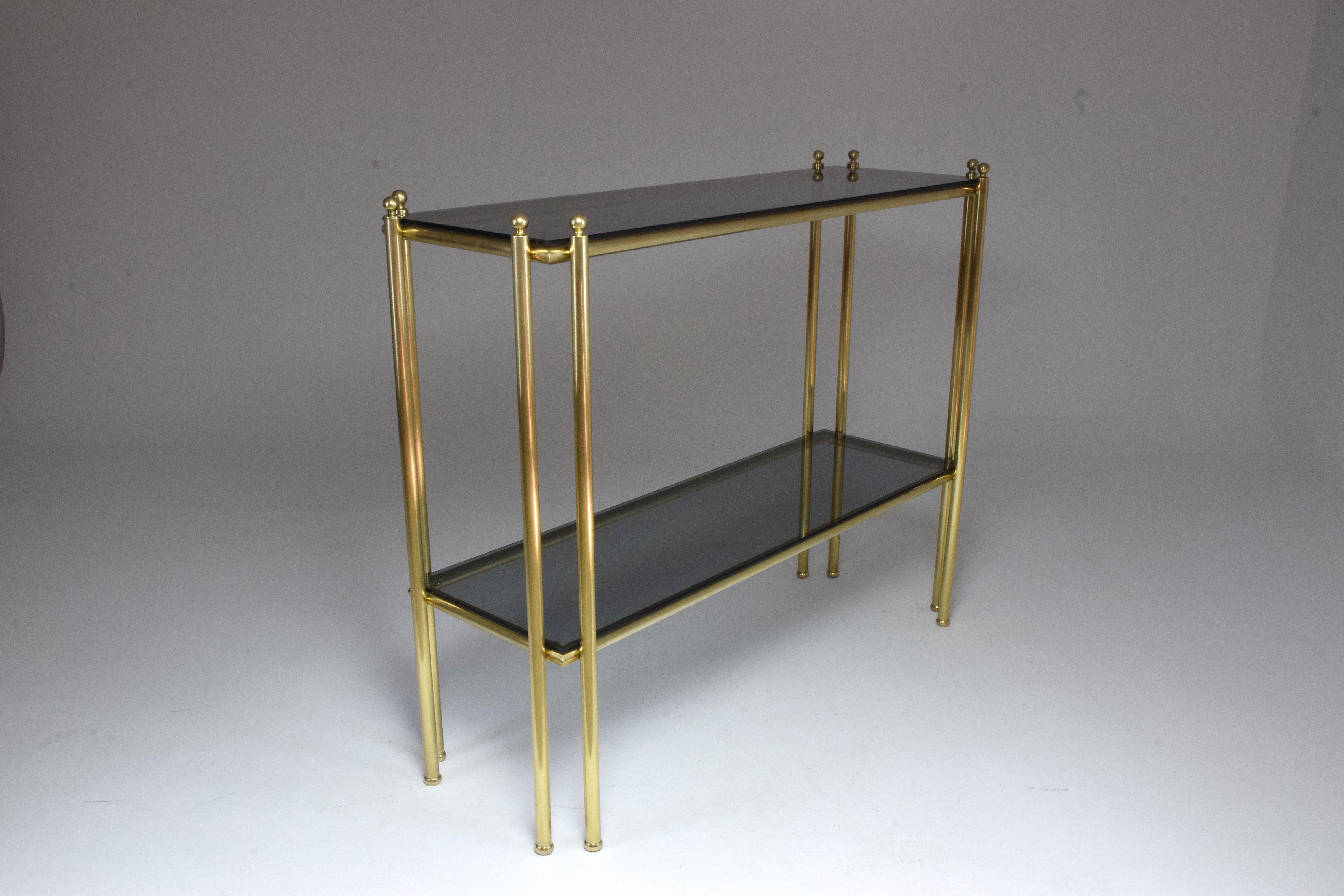 An elegant French 20th century vintage console table designed in France, in the 1970s composed of a solid gold polished brass tubular structure in Art Deco style.
The smoked glass has been replaced on the two-tiered console and the brass