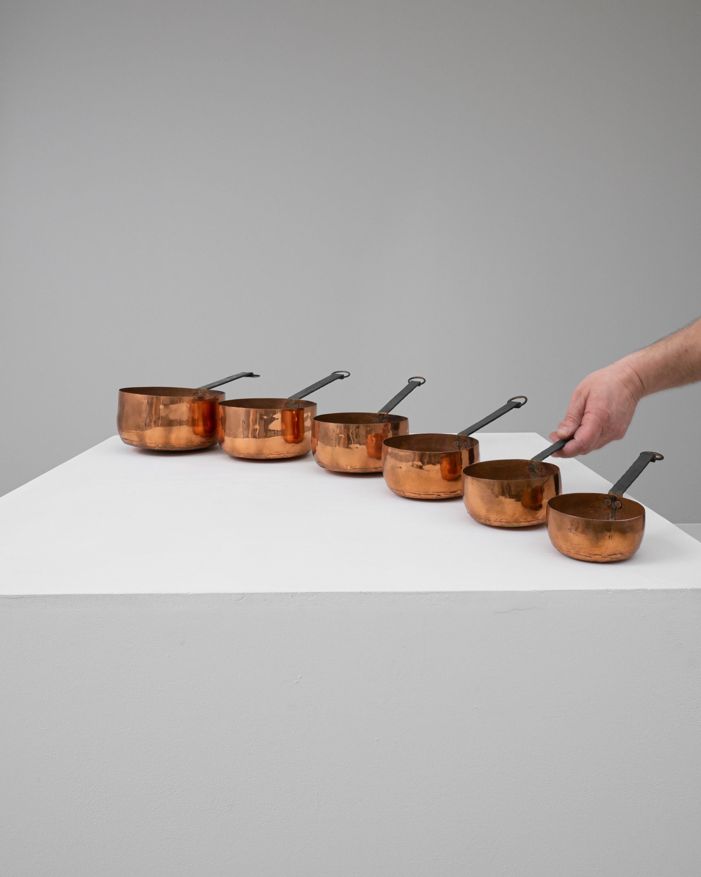 Elevate your culinary experiences with this exquisite set of six 20th-century French brass pots. Artfully crafted with the finest brass, these pots boast a radiant, sun-kissed hue that promises to warm the aesthetics of any kitchen. The graduated