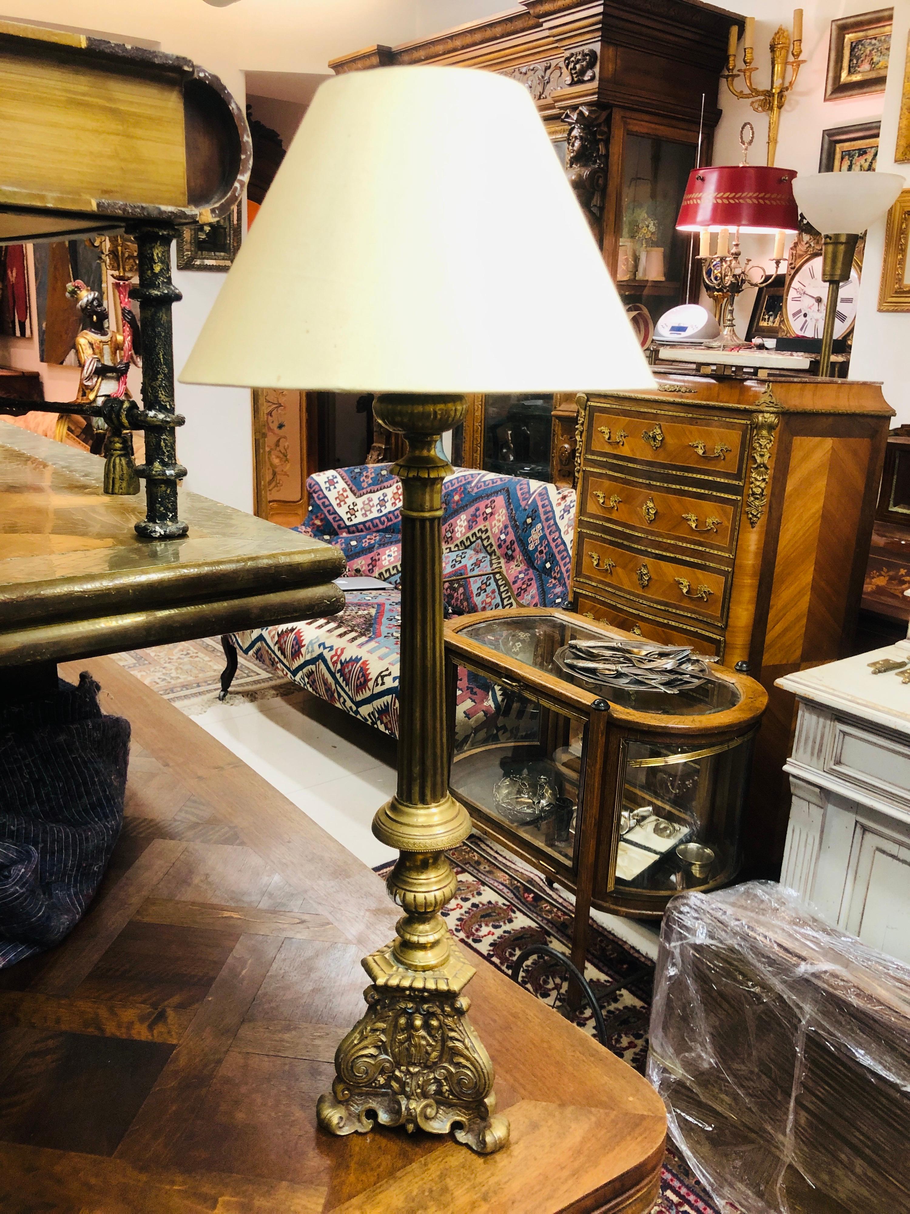 French table lamp standing on richly decorated brass base with small figures on the bottom.
France, circa 1920.