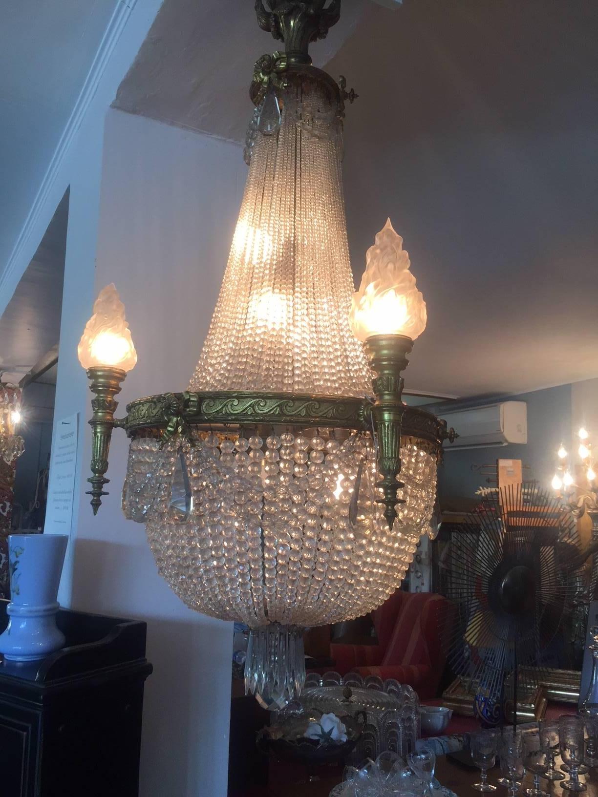 20th century bronze balloon chandelier with crystal and glass pendants.
There are four glasses torchlights. The structure chandelier is made with nice bronze sculpted elements. This is a very elegant chandelier which could be ideal in a living room