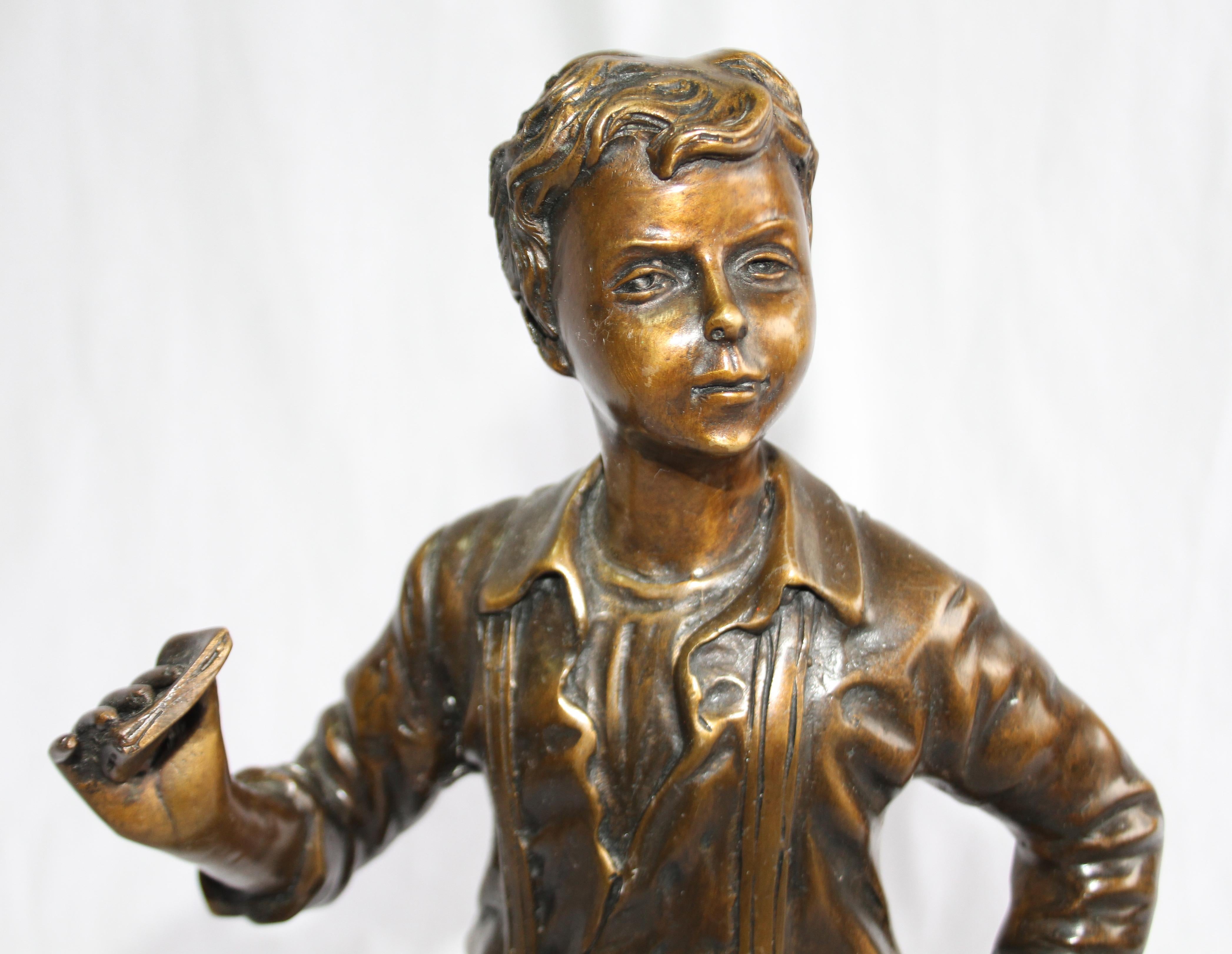 A bronze figure of a boy. French, mid to early 20th century. Mid brown patination. Shown standing wearing braces and breeches. On a circular base.