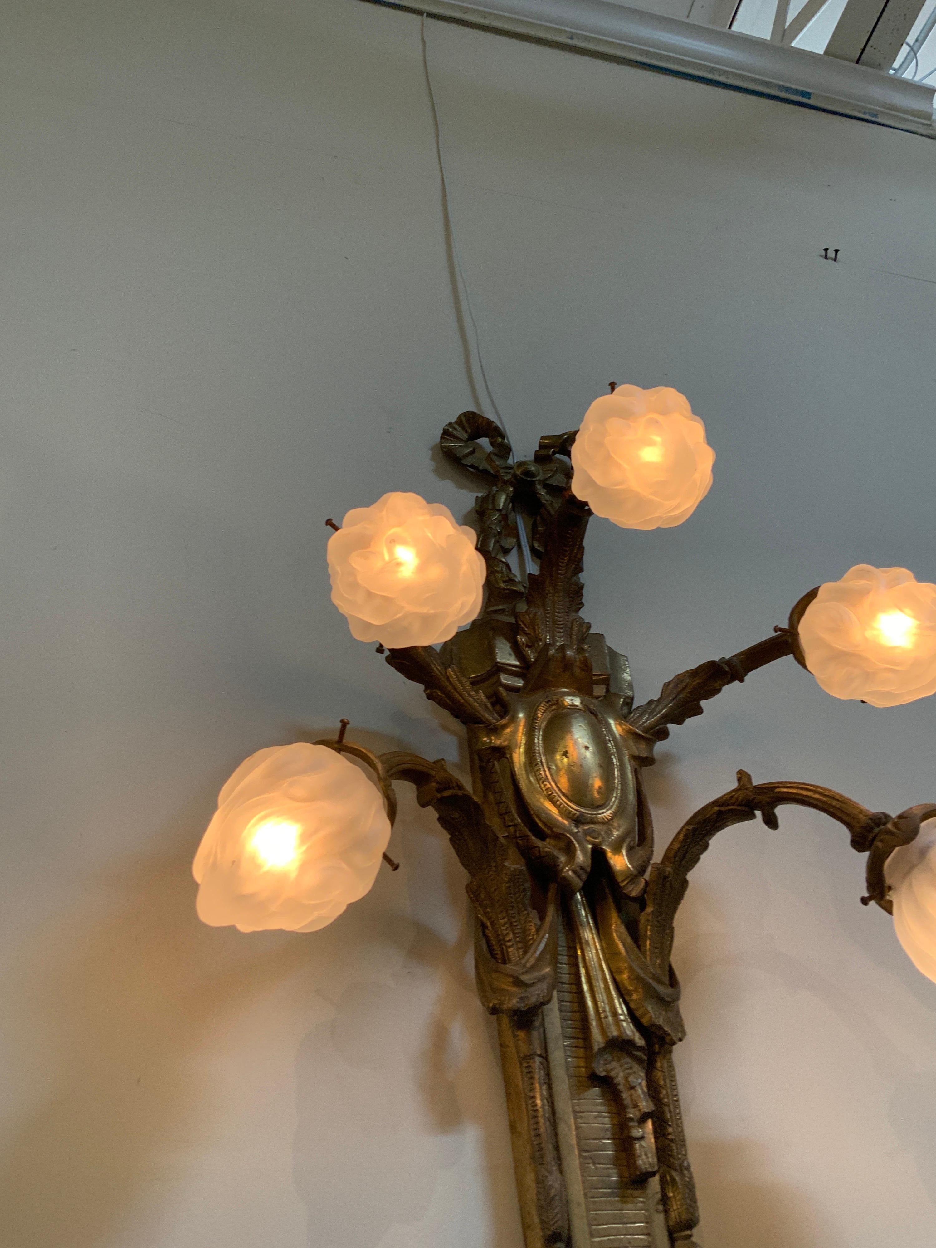 This pair of bronze wall sconces originate from France, circa 1920.