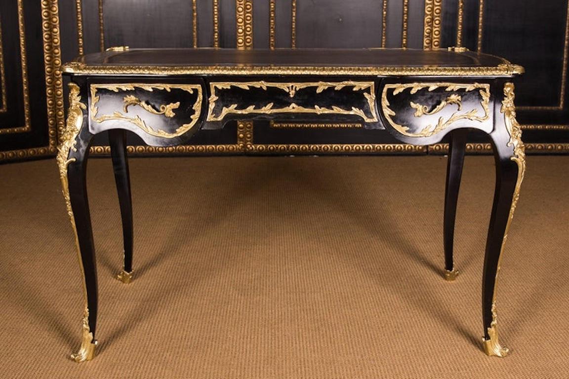 Base con telaio passivo a quattro lati, ebanizzato nero, su quadrati alti ed elegantemente curvati. Incorporato in accessori in ottone finemente cesellati. Piano del tavolo leggermente sporgente con rivestimento in bronzo decorato e inserto in