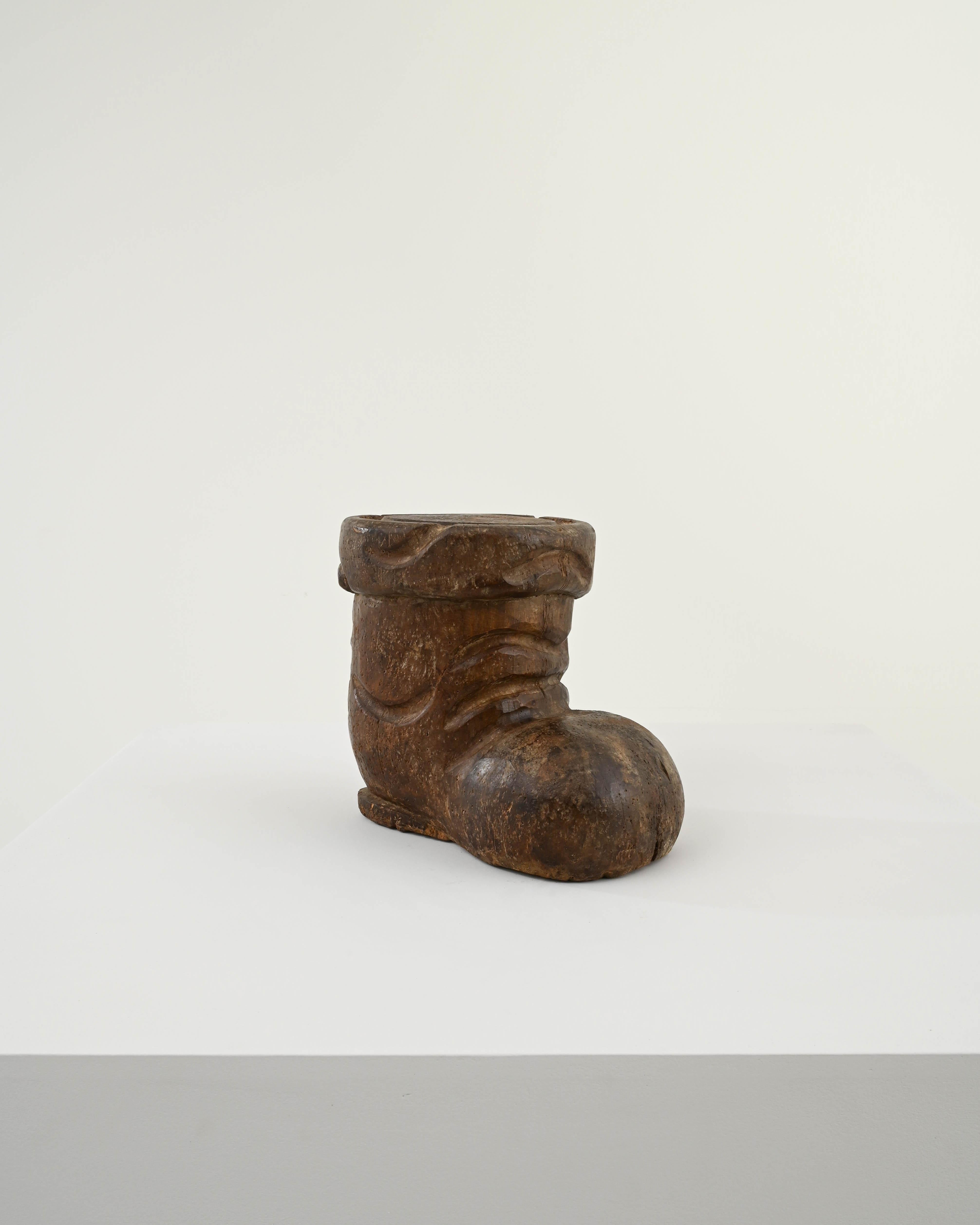 Entrez dans un charme fantaisiste avec cette décoration de bottes en bois sculpté française du 20e siècle. Habilement fabriquée, cette botte en bois capture l'essence d'une chaussure bien usée, avec des détails sculptés de façon complexe qui mettent