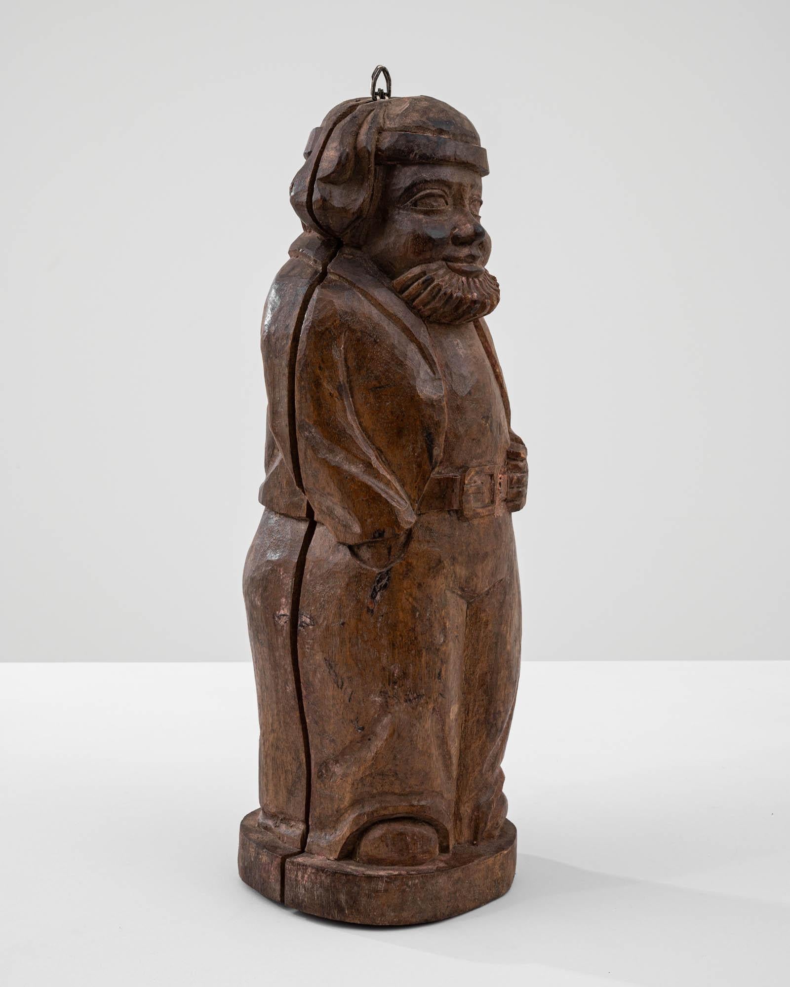 Embrace the whimsical charm of this 20th Century French Carved Wooden Man Decoration, a delightful portrayal of a bearded figure dressed in cozy pajamas venturing out into the cold. The unique design allows the figure to open in half, revealing a