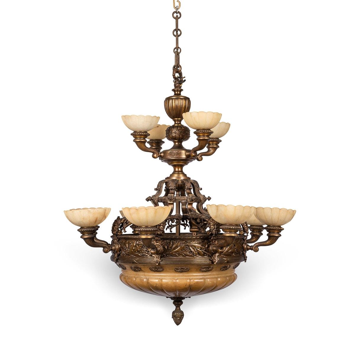 Antique early 20th Century French Empire style cast bronze and alabaster 12 bulb chandelier. Decorated with laurel leaves, reeded boarders and branches applied with Bacchus masks and acanthus leaves. Alabaster is a natural translucent stone that