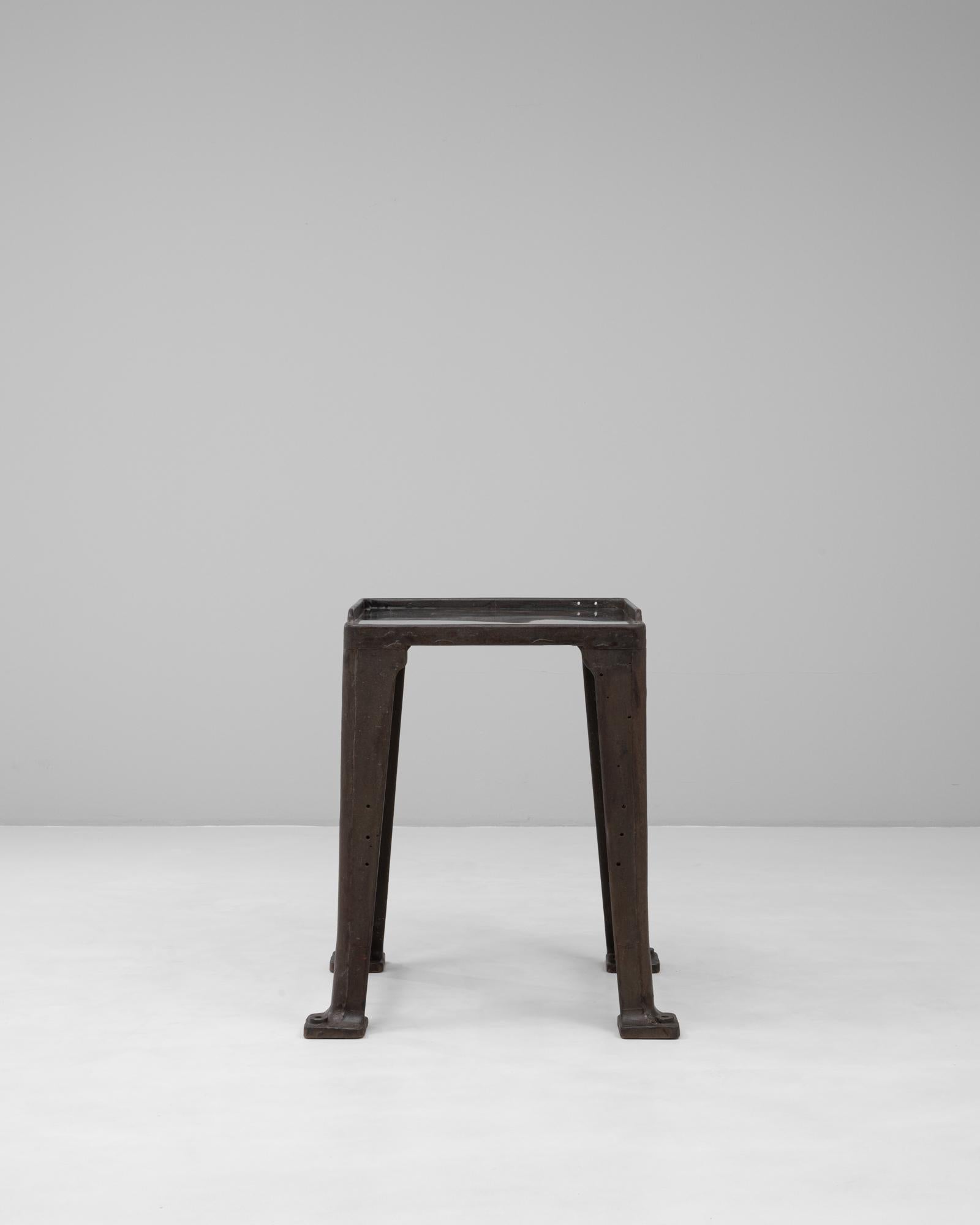 Cette table de travail industrielle française du XXe siècle incarne la force utilitaire et le design intemporel. La base en fonte solide présente des lignes architecturales audacieuses et une patine sombre et vieillie qui souligne ses origines