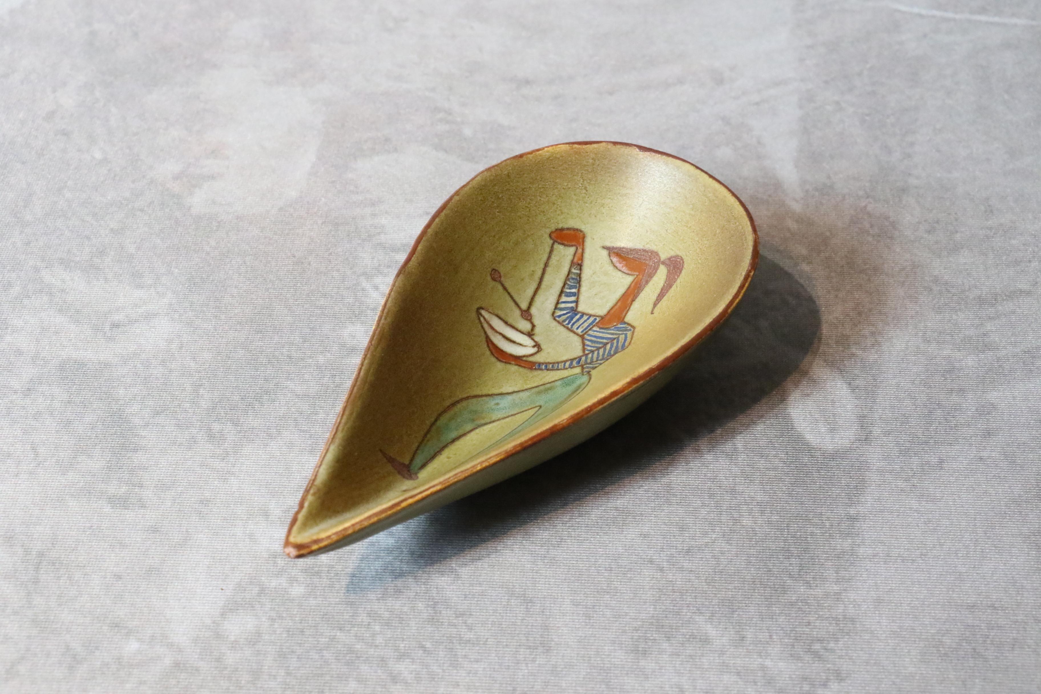 Tasse en céramique blanche française du 20e siècle par René Maurel, années 1970.

Cette tasse en céramique est finement décorée d'une figure féminine. Le bol est émaillé d'un ton ocre et de bordures brunes. 
Elle est signée ci-dessous. 
Il est
