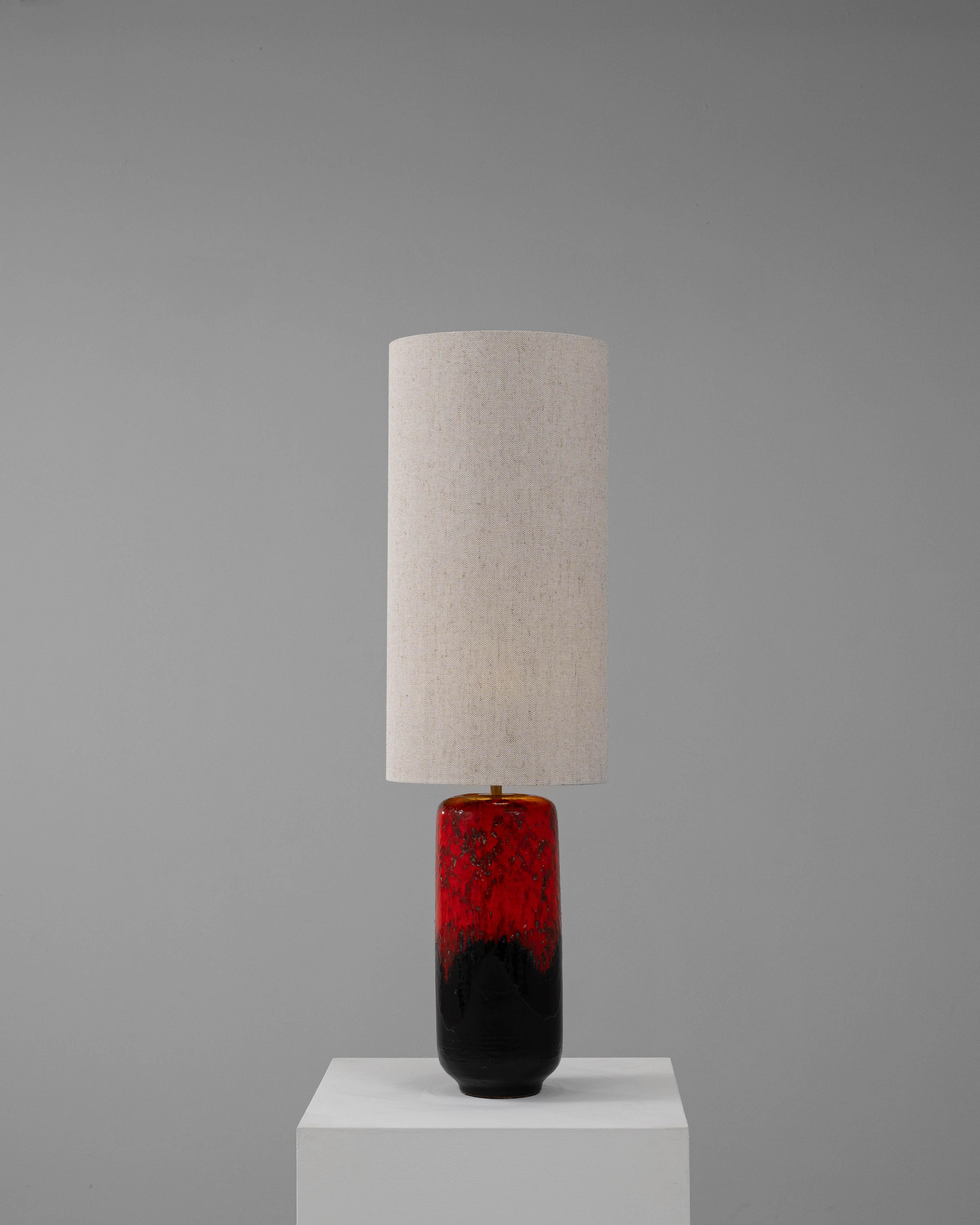 Cette lampe de table en céramique française du 20e siècle est une pièce qui attire l'attention et qui dégage un charme vintage. La base en céramique audacieuse présente un glaçage rouge et noir frappant avec une finition texturée, lui conférant un