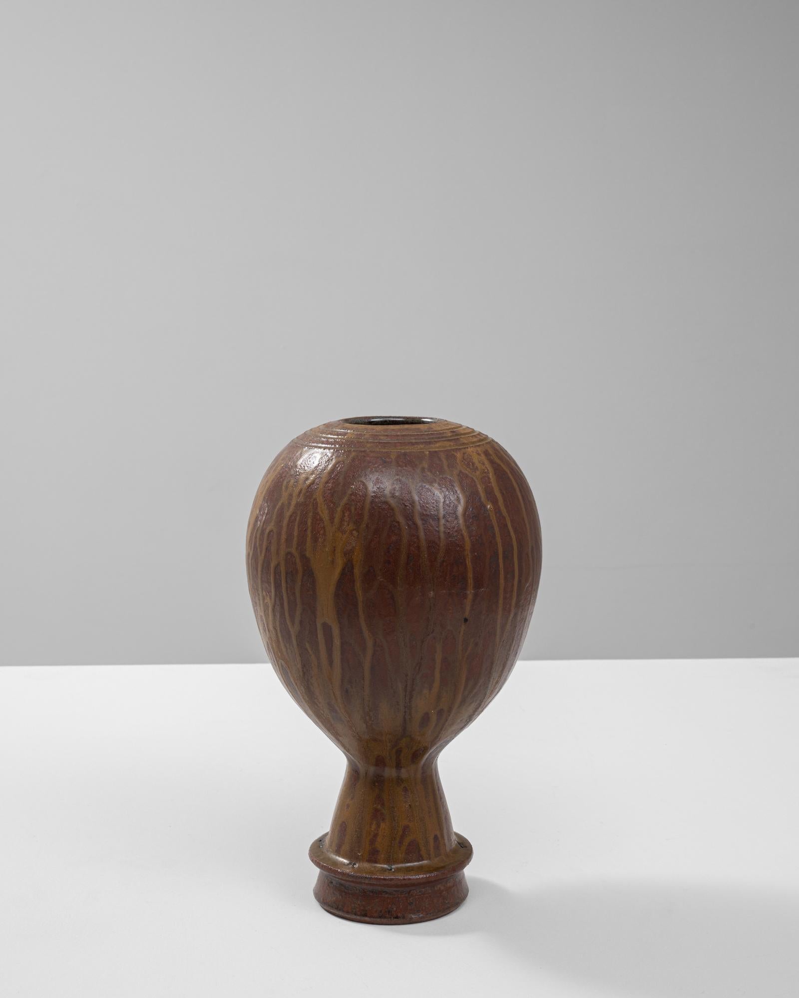 Questo vaso in ceramica francese del XX secolo presenta un design scultoreo unico, che unisce l'artigianato tradizionale all'espressione artistica. Il corpo bulboso è caratterizzato da un ricco smalto marrone lucido con sottili effetti dorati a