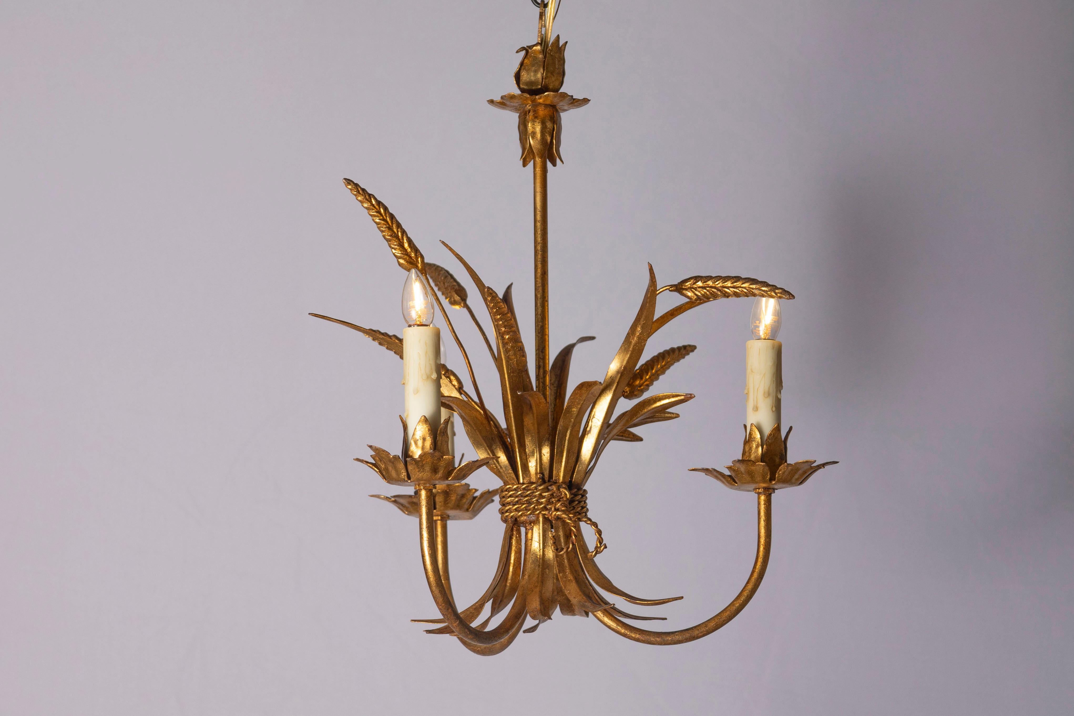 Ce lustre français du XXe siècle incarne l'élégance inspirée de l'esthétique propre à Coco Chanel, mêlant luxe et motifs naturels. Le design est centré sur des gerbes de blé en métal doré, un symbole récurrent dans le décor de Chanel, représentant