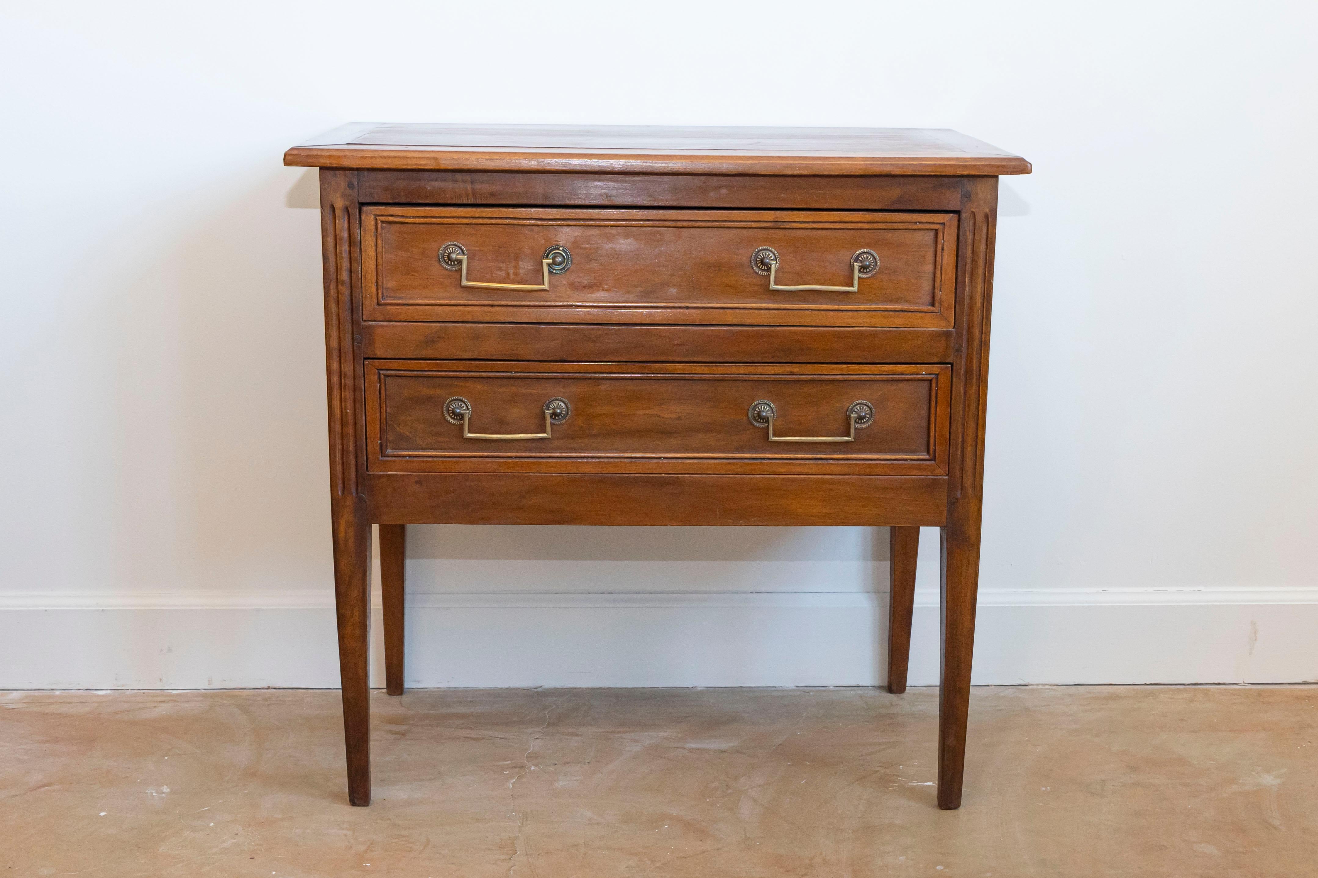 This elegant Louis XVI style chest of drawers, crafted from solid walnut in the 20th century, is a testament to timeless and classy design and craftsmanship. It features two spacious drawers on the front, accented by bronze drop handles, adding a
