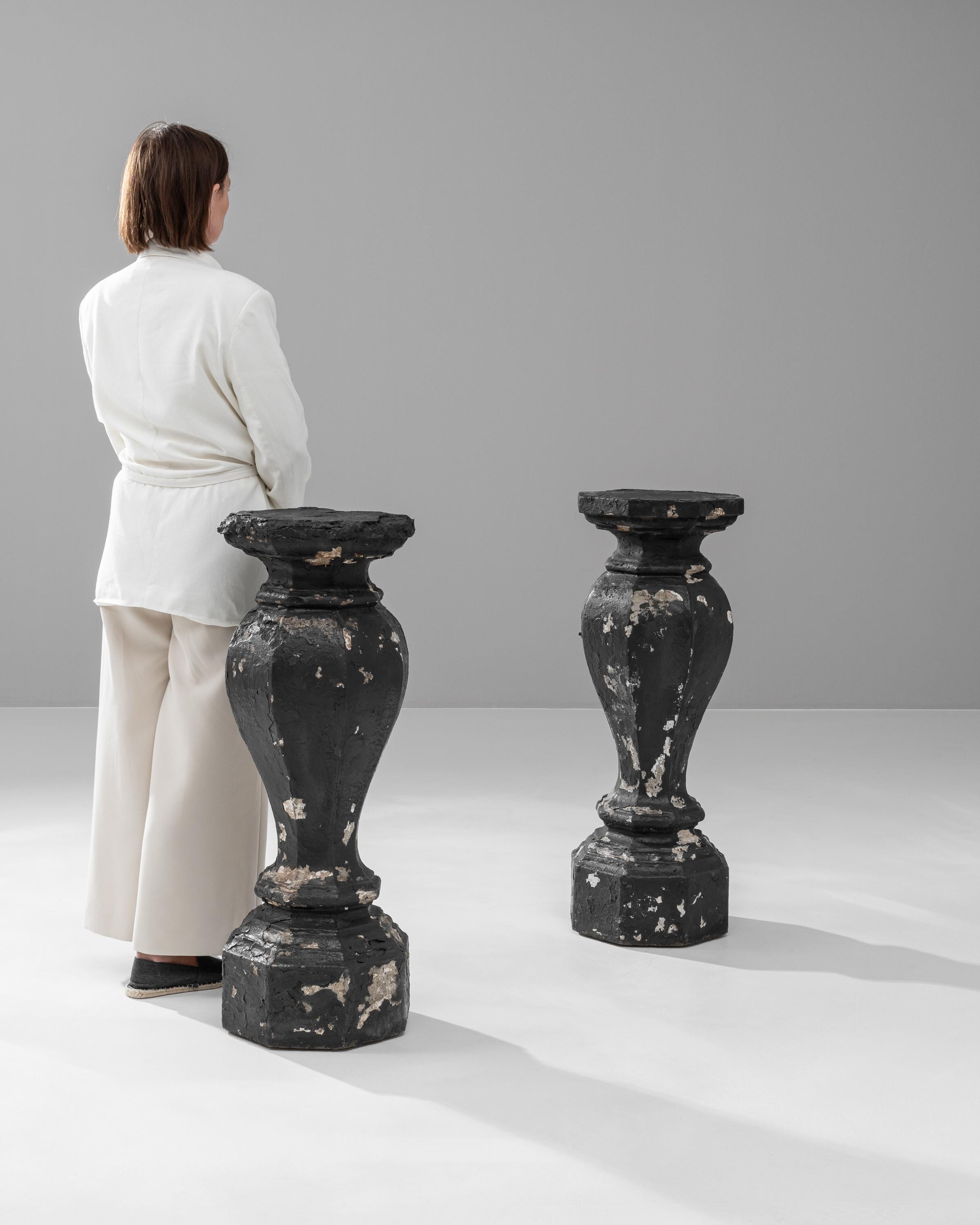 Add an element of classical grandeur to your space with this pair of 20th Century French Concrete Pedestals. These striking pieces showcase the beauty of aged craftsmanship with their heavily distressed black finish and ornate detailing, perfect for