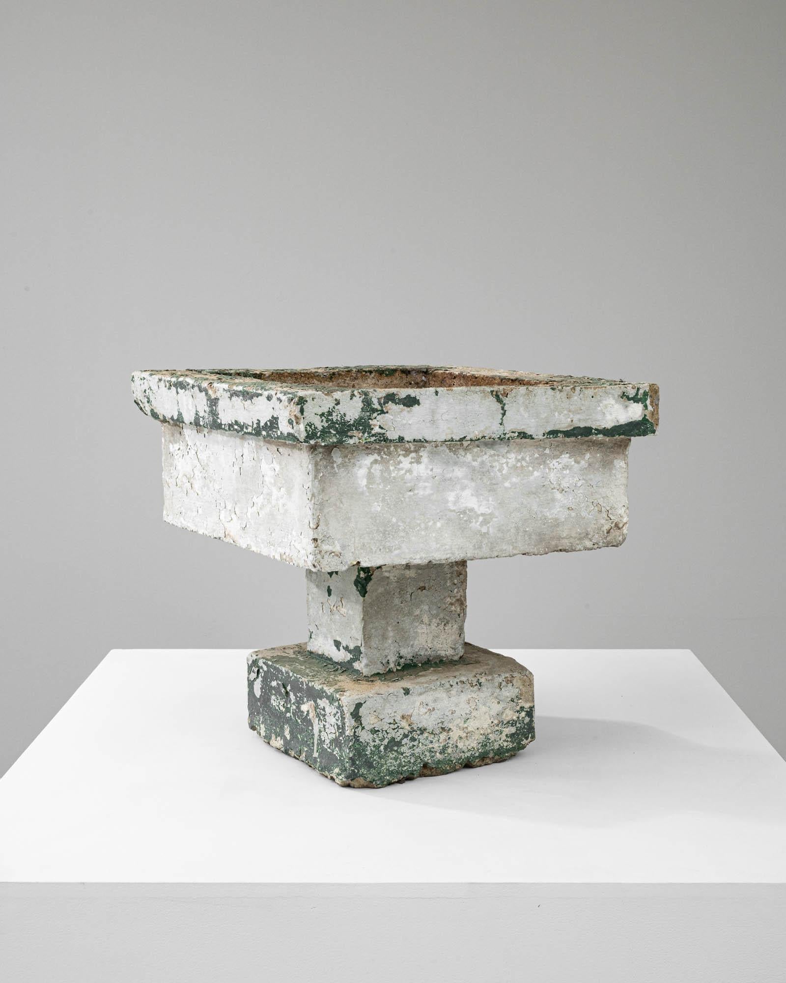 This early 20th Century French Concrete Planter exudes the raw, unrefined beauty of utilitarian design, transformed by time into a work of art. The planter, with its weathered texture and remnants of green paint, possesses a unique character that