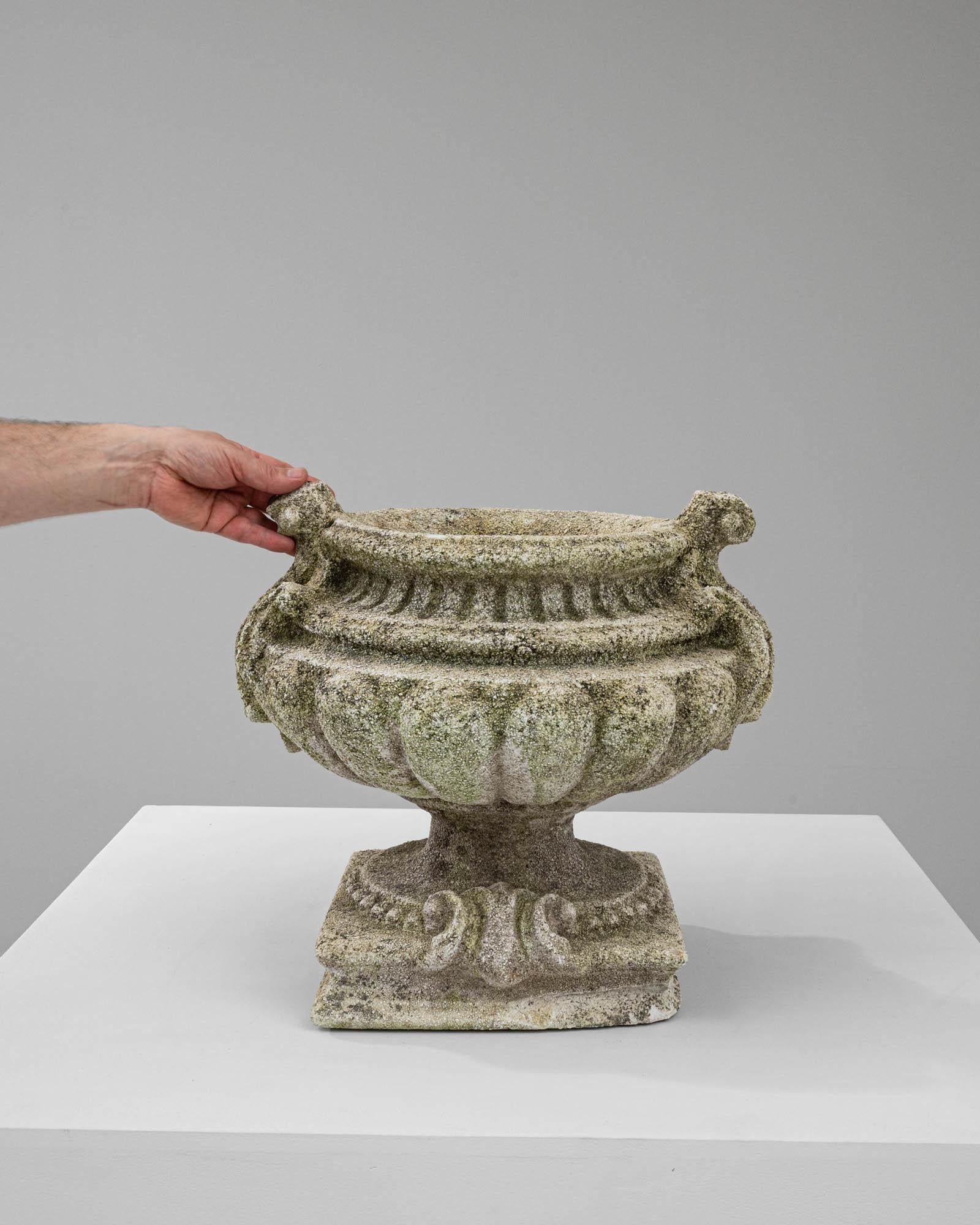 This 20th-century French concrete planter is a stunning piece that combines the robustness of its material with the delicacy of its ornate design. It features classical detailing, such as gadrooning and scrollwork, which are softly highlighted by