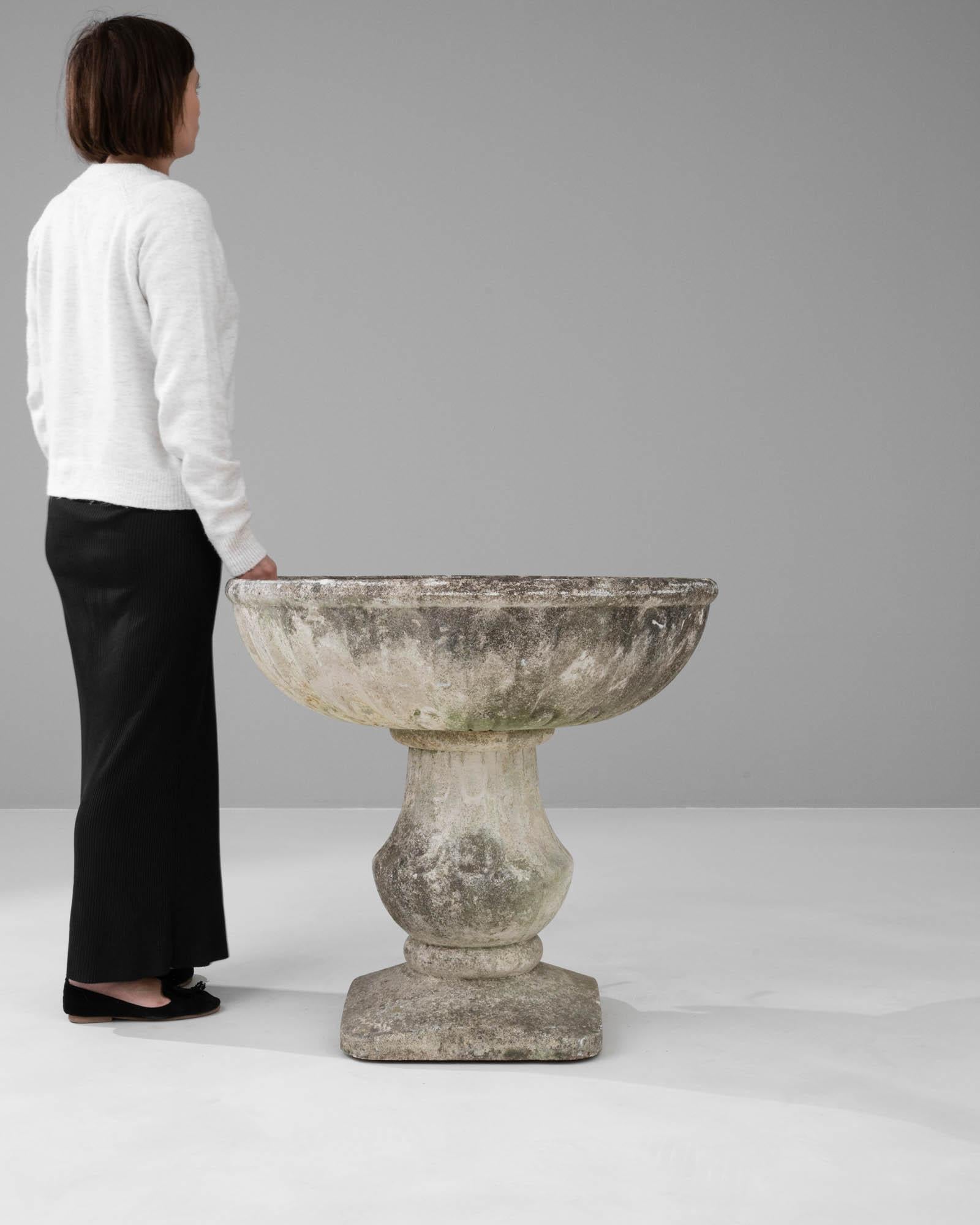 This 20th-century French concrete planter is an exquisite example of garden architecture, blending robust materiality with classical aesthetics. Its wide, open bowl rests upon an elegant, fluted pedestal, mirroring the style of ancient Grecian urns.