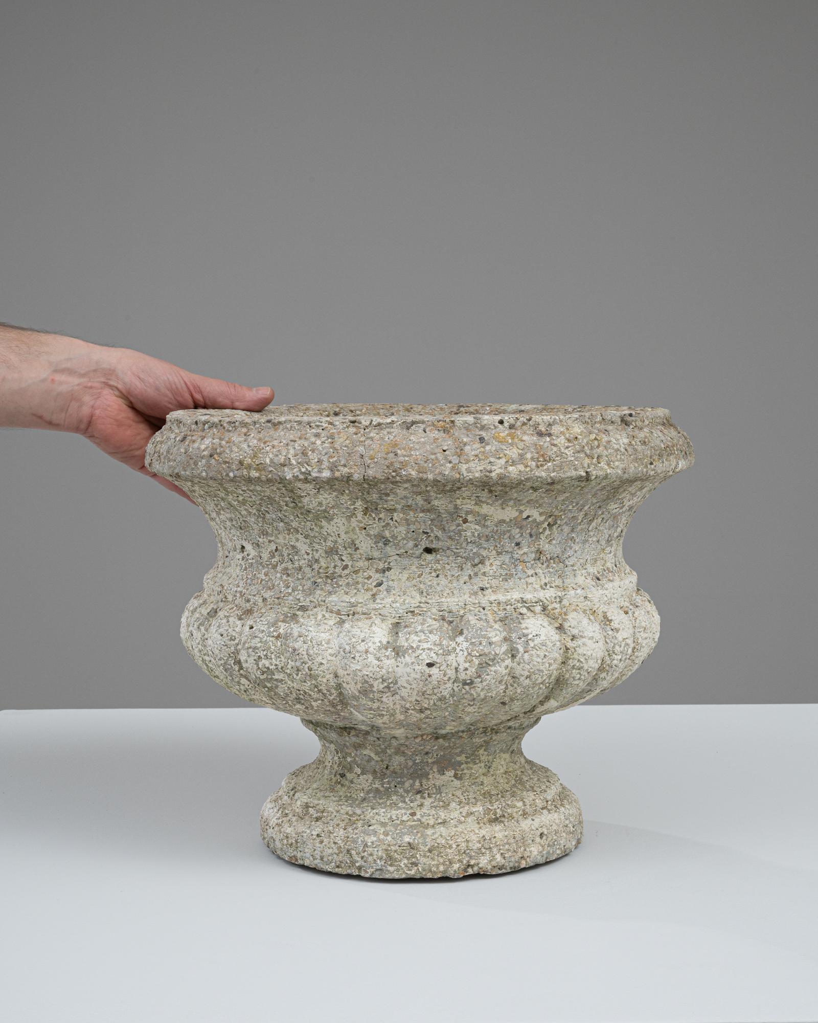 This 20th-century French concrete planter embodies a timeless aesthetic with its classic design and speckled, stone-like finish. Its robust, bulbous shape and wide, flared rim provide a solid foundation for displaying a lush array of plants or