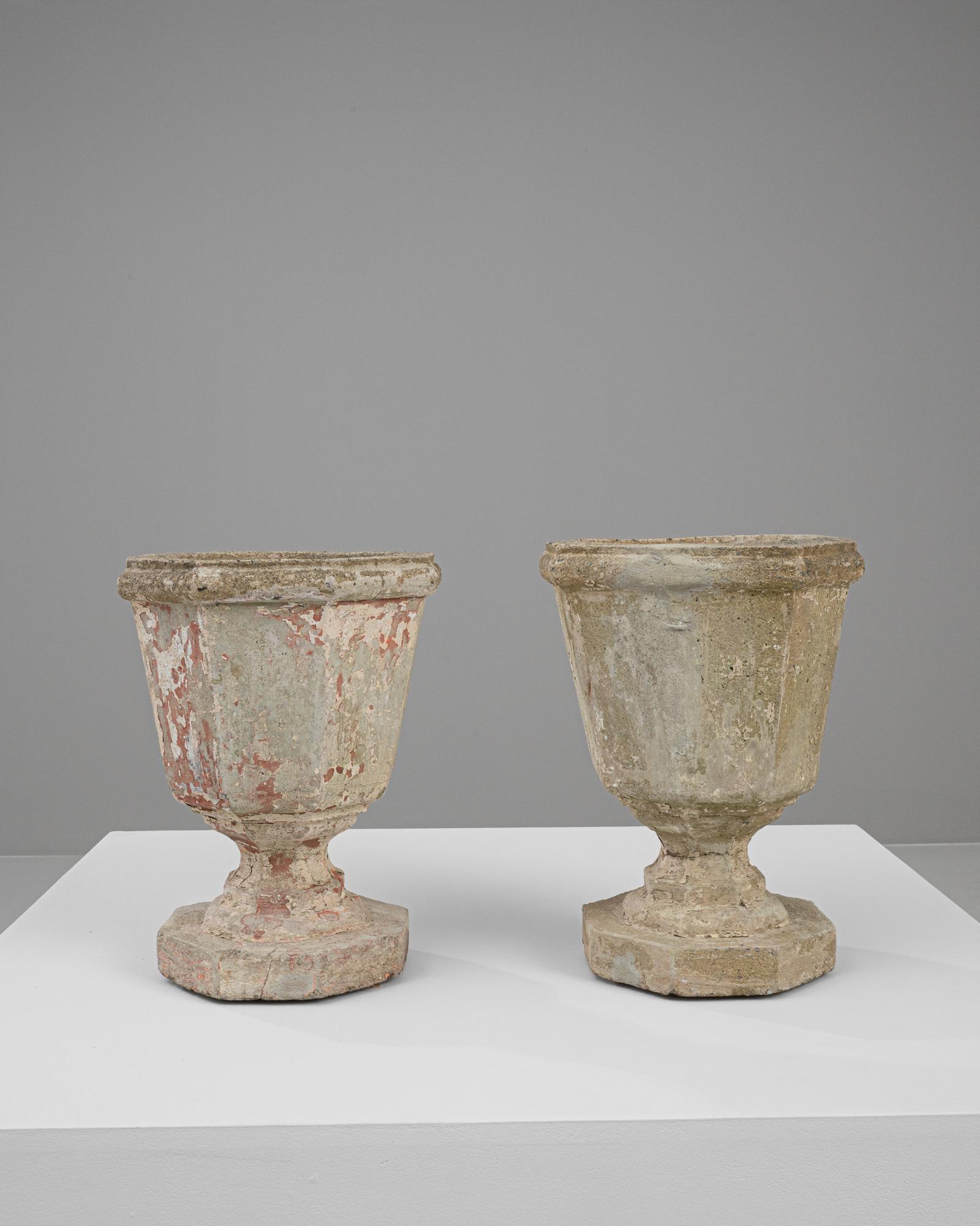 Enhance your outdoor or indoor living space with this pair of 20th-century French concrete planters, each boasting a distinct patina that adds character and a storied element to your decor. These robust planters feature a classic design with a
