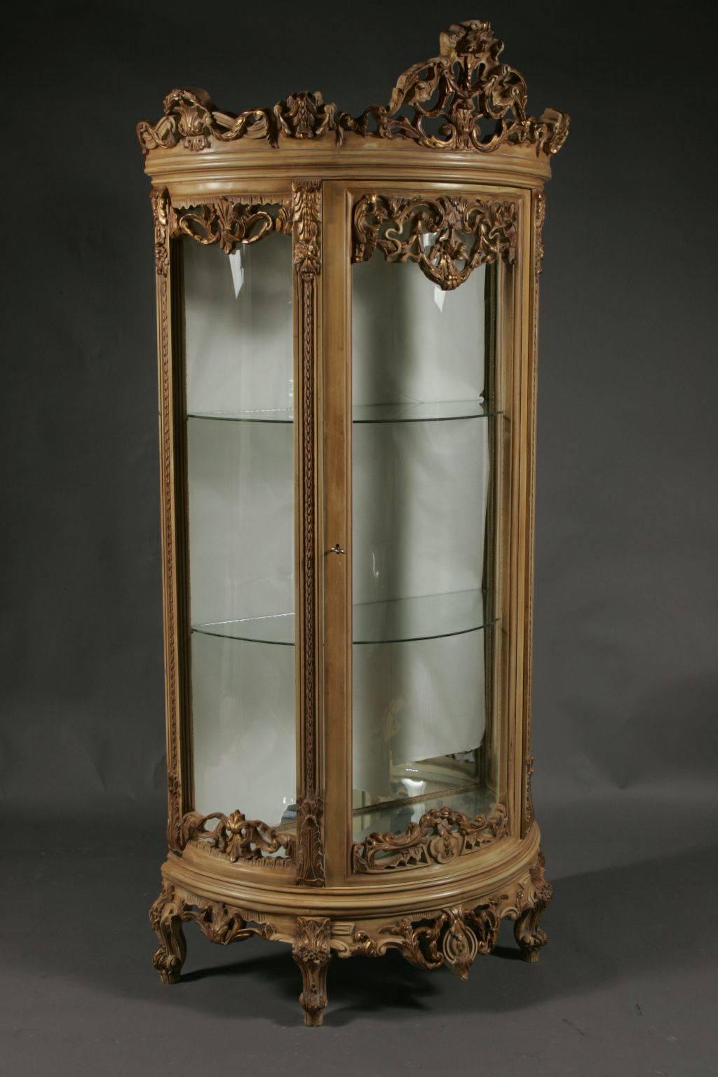 Beautiful French Vitrine.
Solid, finely carved beechwood, gilded. Half round, cambered and glazed on three sides corpus. On curved feet. Single doored, prominent border. Cartouche-formed frame with cartouche-formed broken through cornice.

The