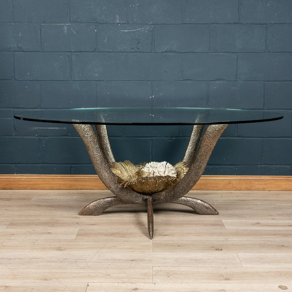 Rare et impressionnante table de salle à manger de Jacques Duval-Brasseur, fabriquée en France vers les années 1970. L'épais verre ovale est soutenu par un cadre sculptural bicolore entièrement en laiton, qui renferme un corail en son centre. Signé